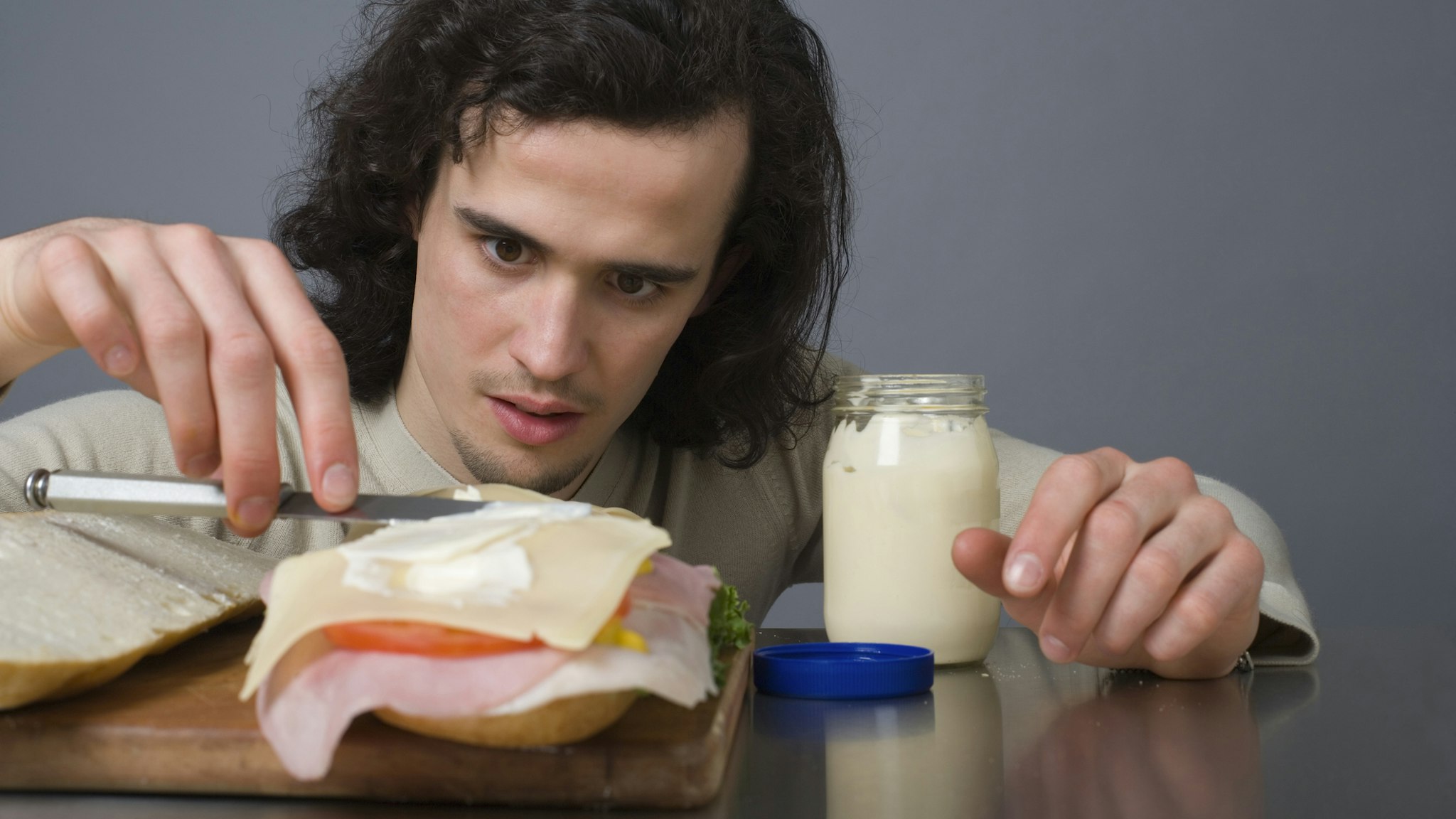 Man putting mayonnaise on a sandwich