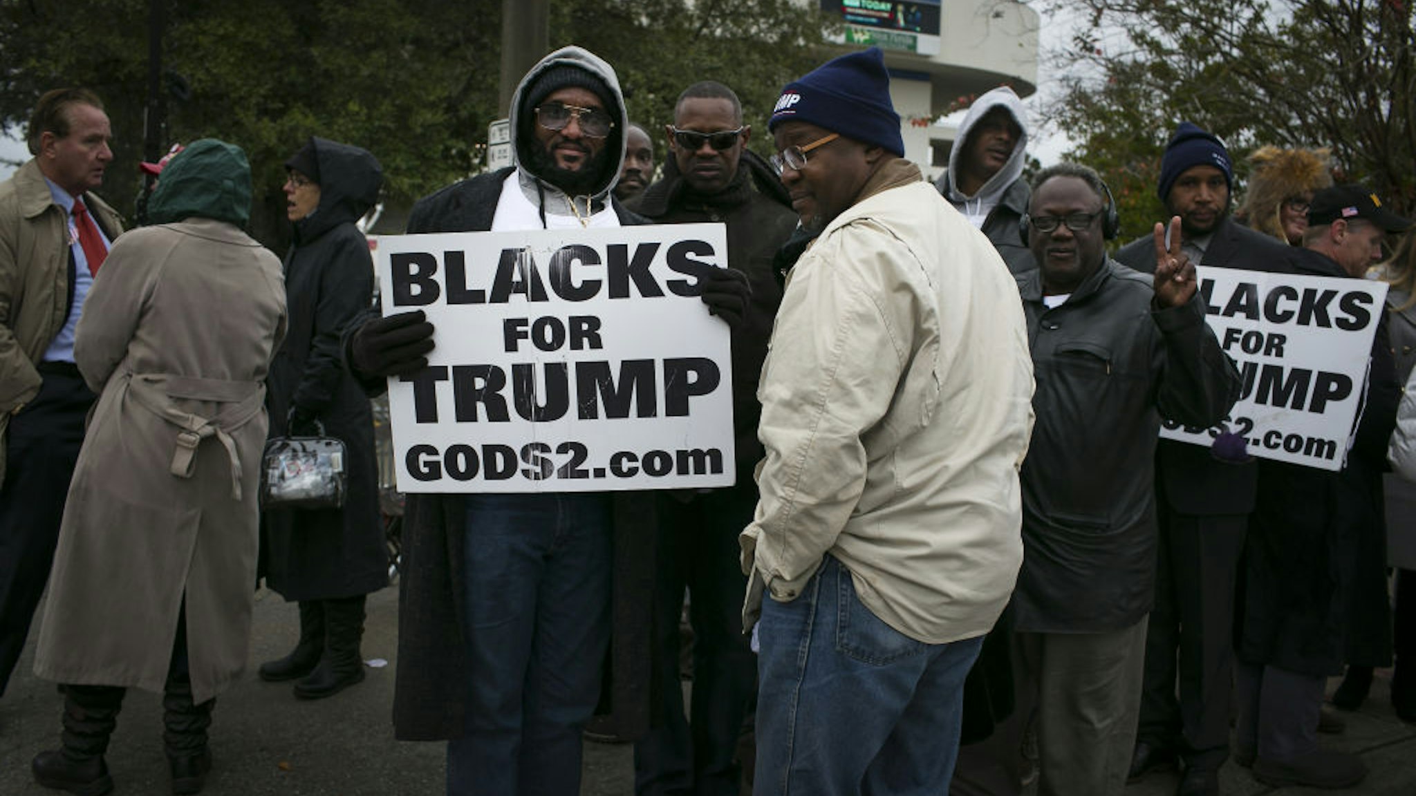 Attendees hold "Blacks For Trump" signs while waiting in line for a campaign rally with U.S. President Donald Trump in Pensacola, Florida, U.S., on Friday, Dec. 8, 2017.