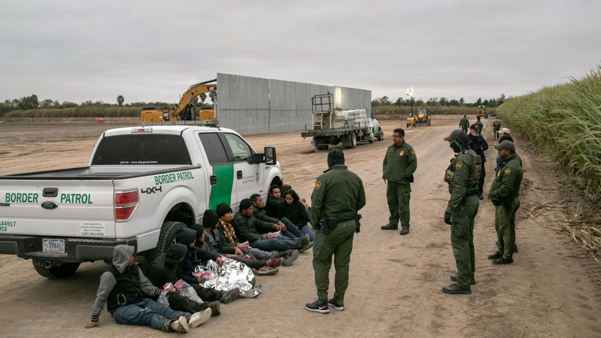 U.S. Border Patrol agents detain undocumented immigrants caught near a section of privately-built border wall under construction on December 11, 2019 near Mission, Texas. The hardline immigration group We Build The Wall is funding construction of the wall on private land along the Rio Grande, which forms the border with Mexico. The group, led by former Trump strategist Stephen Bannon claims to have raised tens of millions of dollars in a GoFundMe drive to build sections of wall along stretches of the U.S. southwest border with Mexico. (Photo by John Moore/Getty Images)