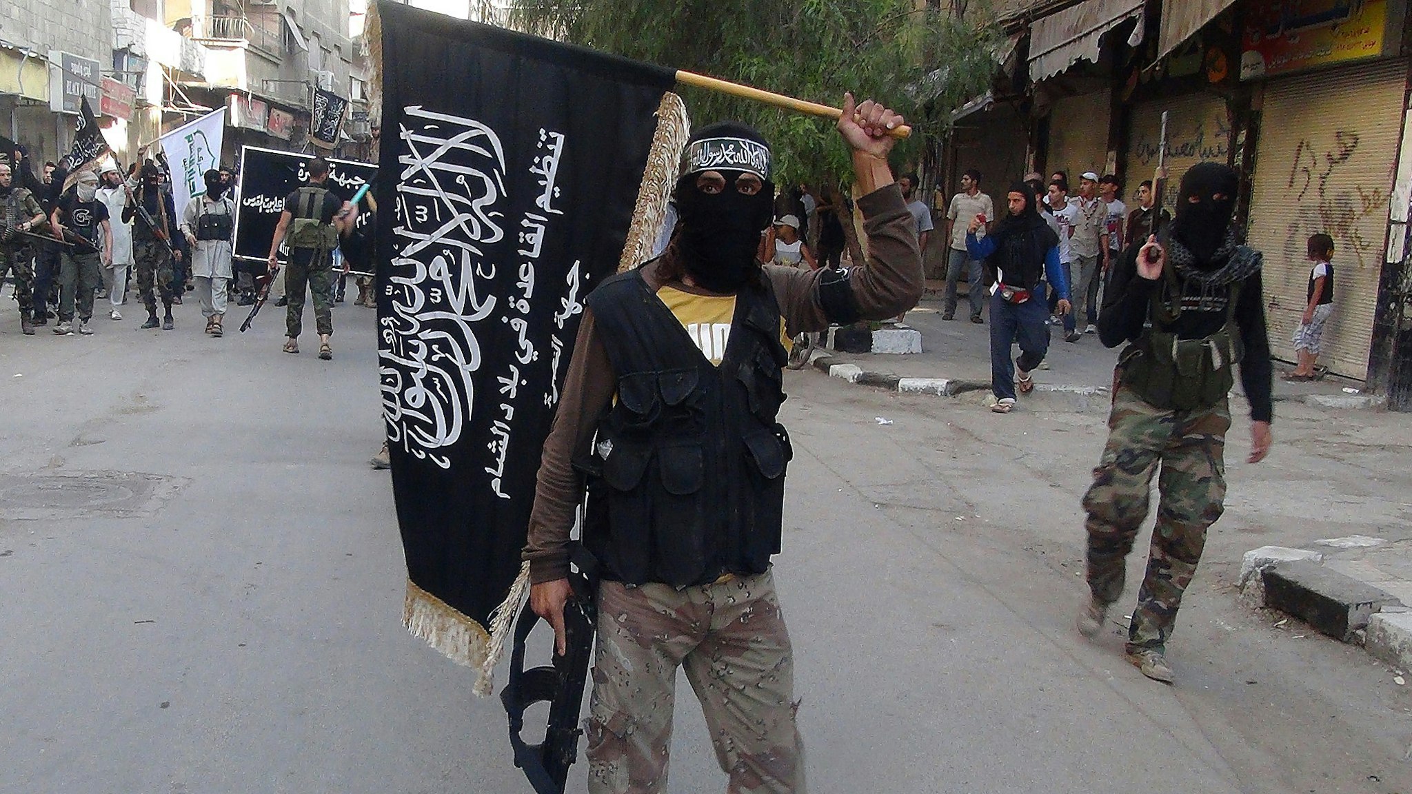 Islamic fighters from the al-Qaida group in the Levant, Al-Nusra Front, wave their movement's flag as they parade at the Yarmuk Palestinian refugee camp, south of Damascus, to denounce Israels military offensive on the Gaza Strip, on July 28, 2014. Israeli shells struck a UN school in Gaza early today, killing 16, as ground troops made a signficant push into the territory despite Palestinian efforts to broker a 24-hour truce. AFP PHOTO/RAMI AL-SAYED