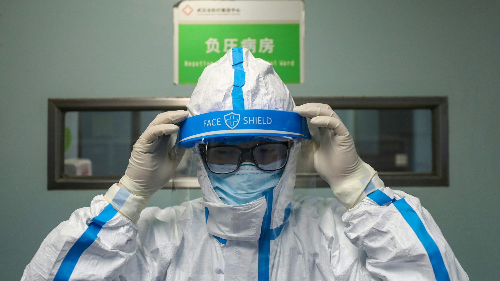 WUHAN, CHINA - FEBRUARY 13 2020: A doctor puts on the isolation outfit before entering the negative-pressure isolation ward in Jinyintan Hospital, designated for critical COVID-19 patients, in Wuhan in central China's Hubei province Thursday, Feb. 13, 2020. The city reported 13,436 new cases of COVID-19 Feb. 12, a big jump after the city combed communities for patients and expanded the capacity to take them in.