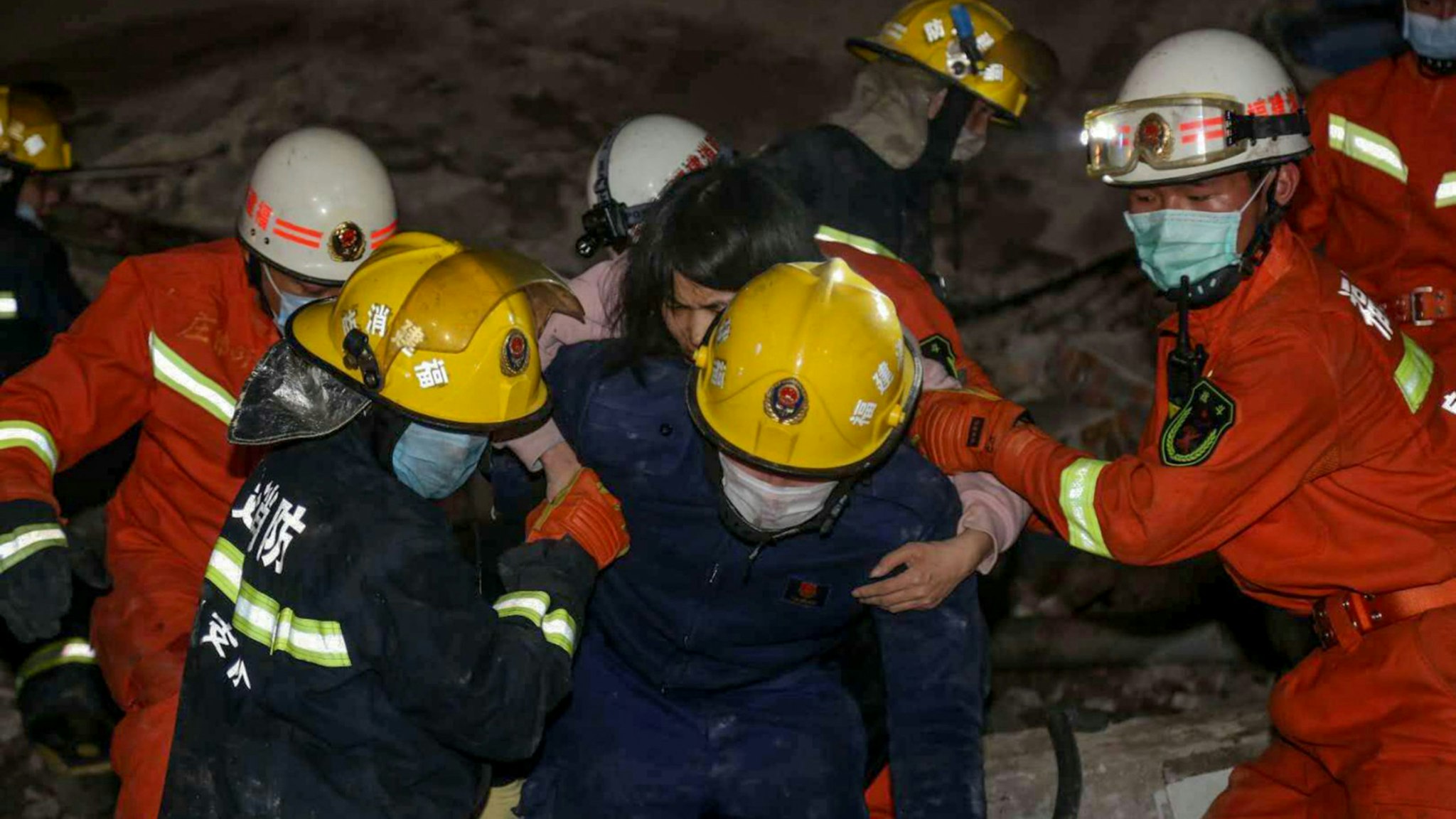A woman (C on the back) is rescued from the rubble of a collapsed hotel in Quanzhou, in China's eastern Fujian province on March 7, 2020. - Around 70 people were trapped after the Xinjia Hotel collapsed on March 7 evening, officials said.