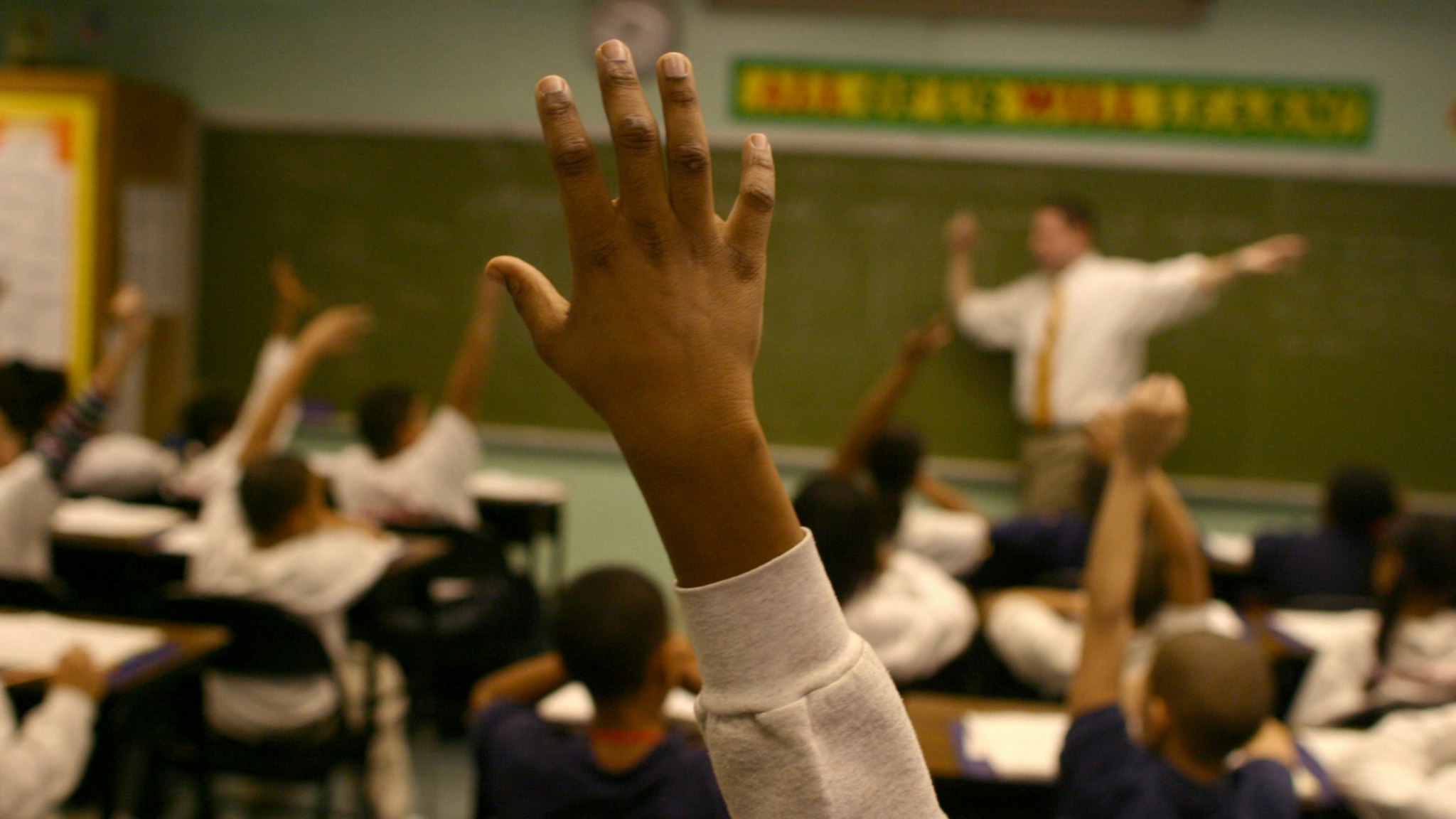 Students raise their hands to answer a teacher's question at the KIPP Academy in the South Bronx, part of a network of public middle schools that is becoming a model for educating poor children.