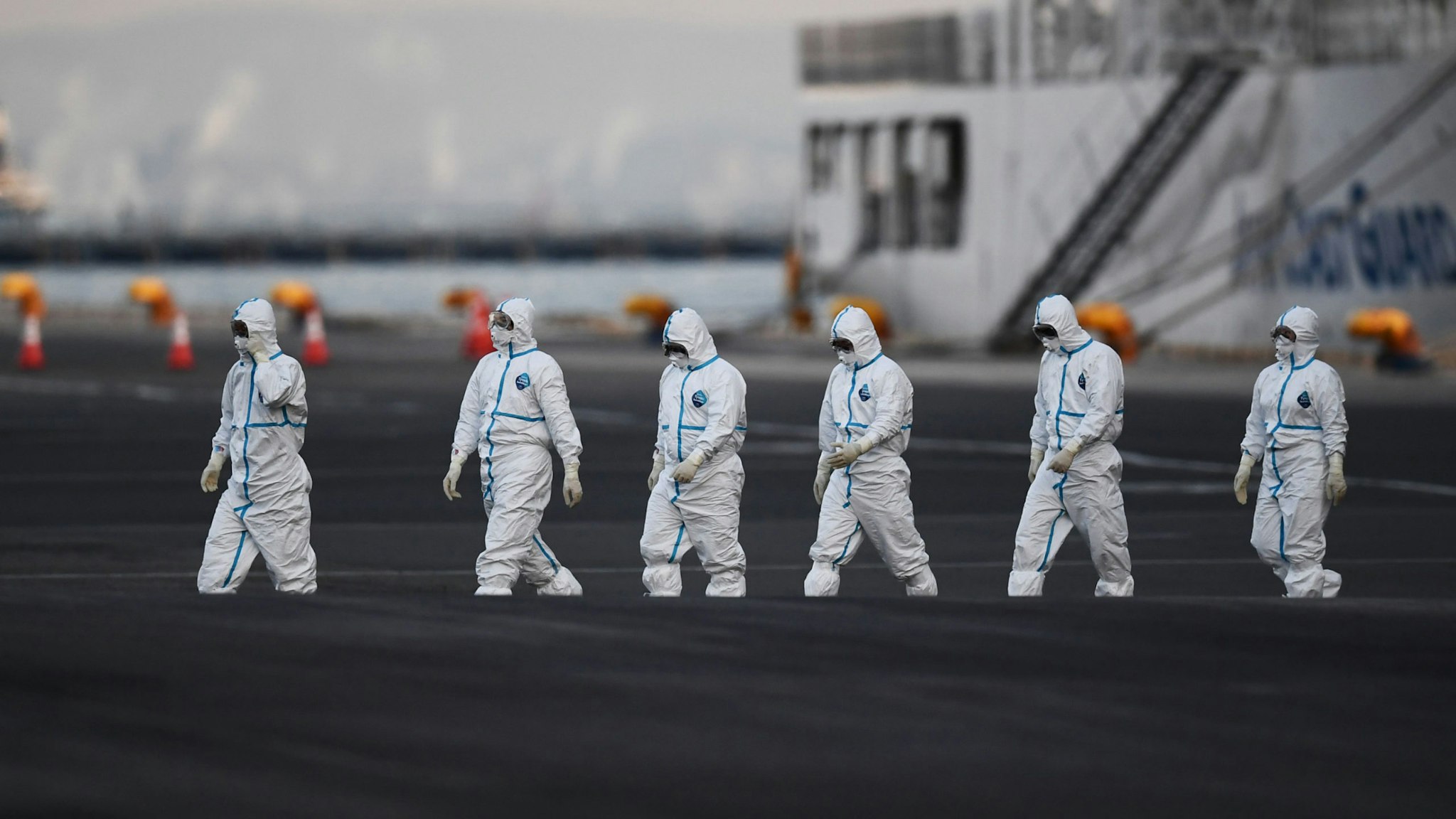 People wearing protective suits walk from the Diamond Princess cruise ship, with around 3,600 people quarantined onboard due to fears of the new coronavirus, at the Daikoku Pier Cruise Terminal in Yokohama port on February 10, 2020.