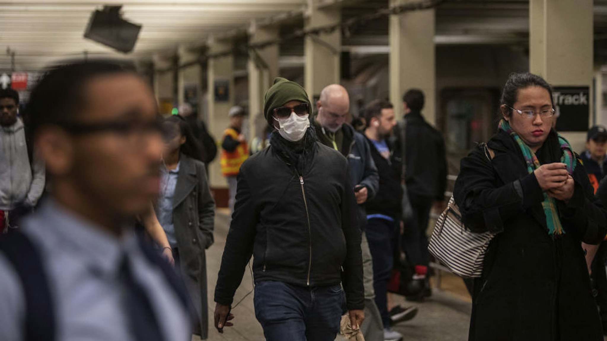 A commuter wears a mask while walking through a subway station in New York, U.S., on Monday, March 9, 2020. In a series of tweets Sunday, New Yorkers were encouraged by Mayor Bill de Blasio to avoid the busiest times of the subway and bus rush hour by telecommuting, staggering work schedules or walking or biking to work as cases of the coronavirus climb. Photographer: Victor J. Blue/Bloomberg