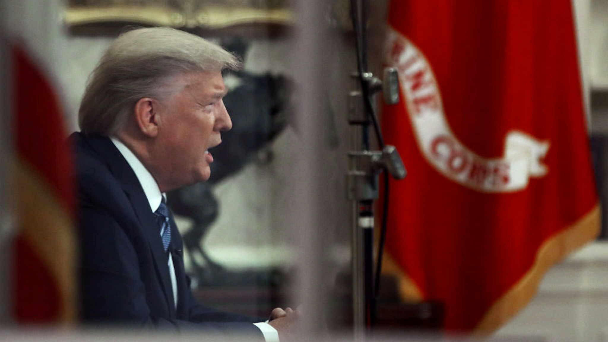 President Donald Trump is seen through a window in the Oval Office as he addresses the nation on the response to the COVID-19 coronavirus, on March 11, 2020 in Washington, DC. (Photo by Mark Wilson/Getty Images)