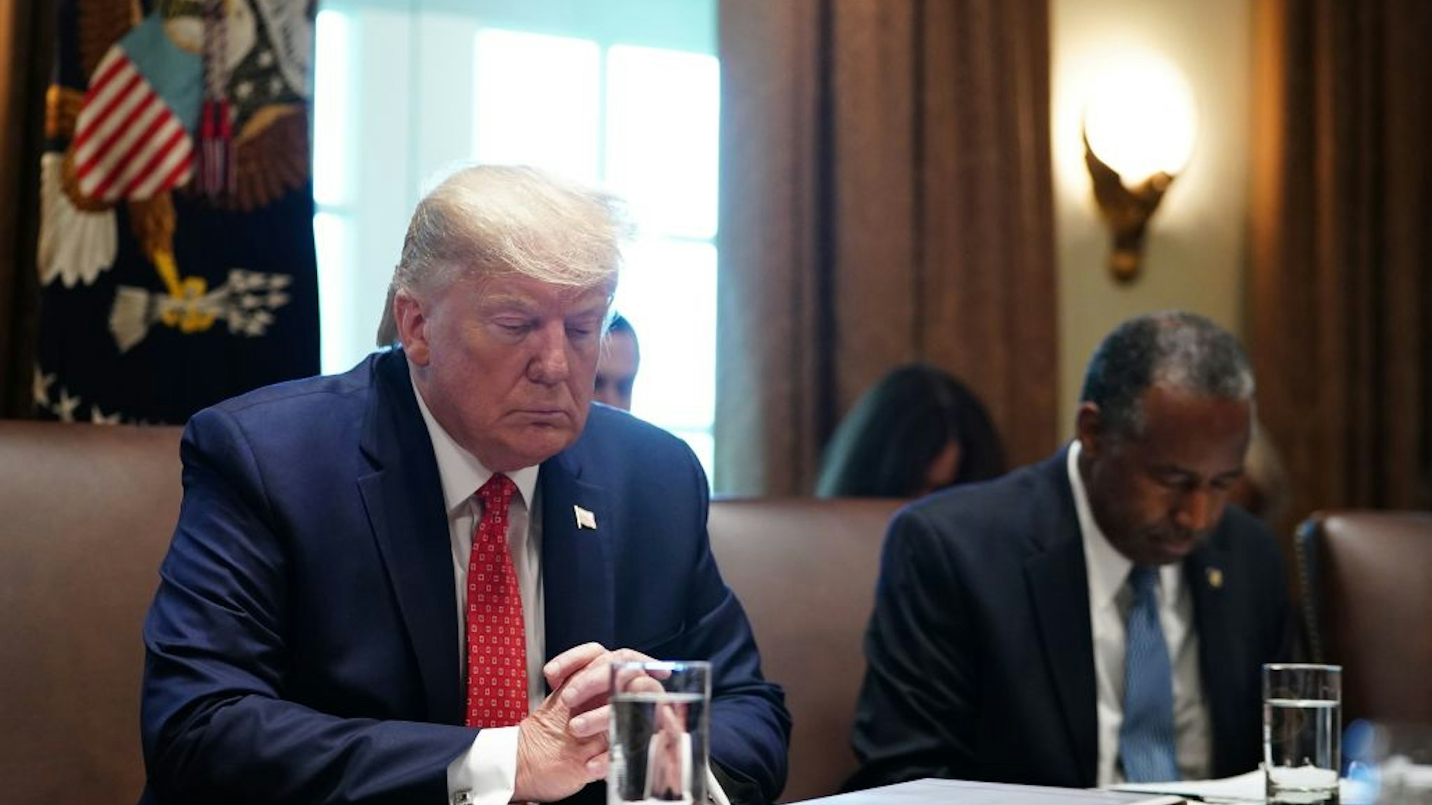 US President Donald Trump prays next to Ben Carson, Secretary of Housing and Urban Development as they take part in a cabinet meeting in the Cabinet Room of the White House in Washington, DC on November 19, 2019.