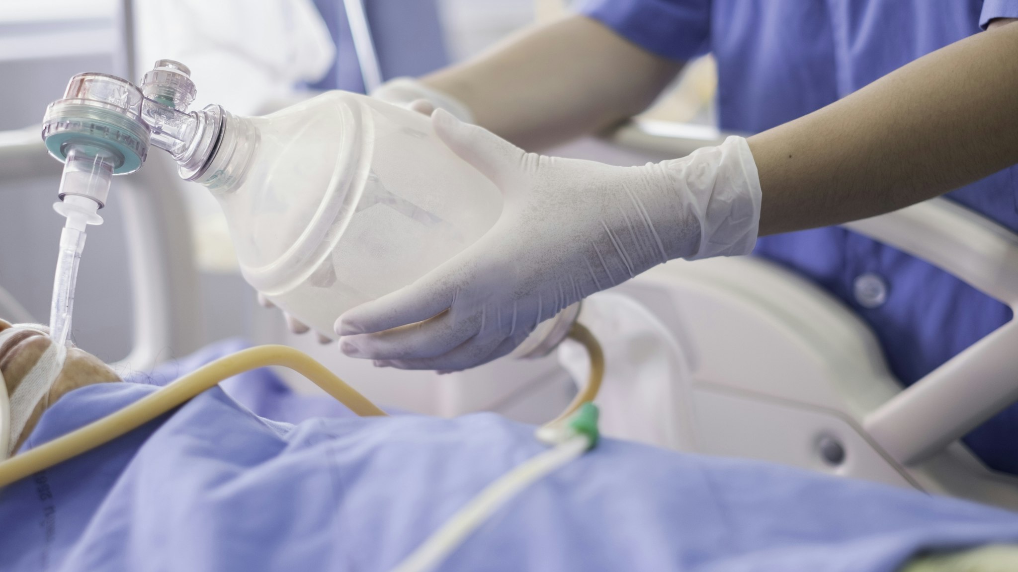Doctor holding oxygen ambu bag over patient given oxygen to patient by intubation tube in ICU/Emergency room - stock photo