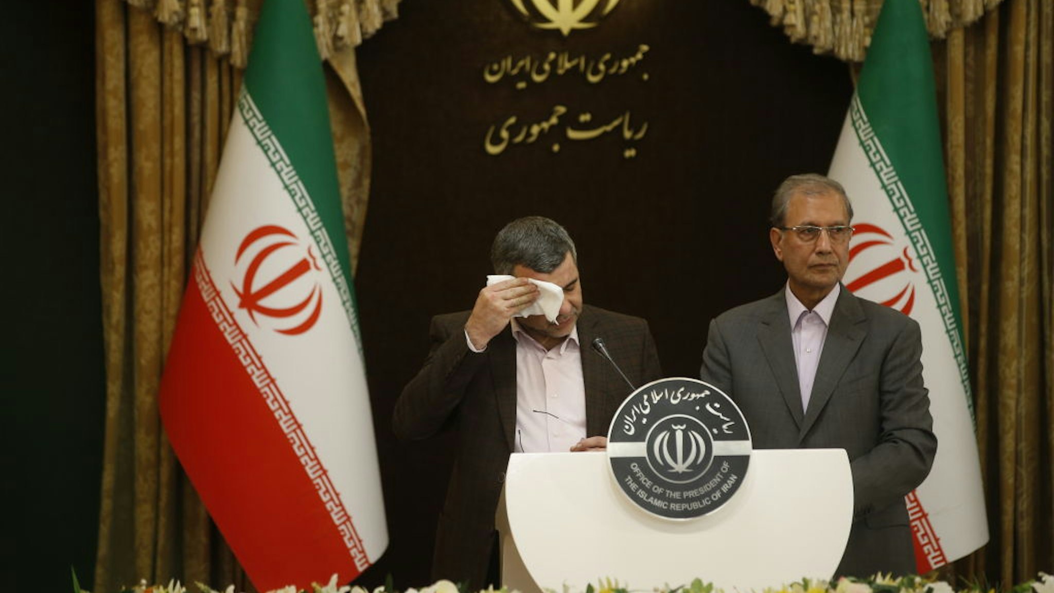 Iranian Deputy Health Minister Iraj Harirchi (L) wipes his sweating as he speaks on his tests positive for coronavirus as he holds a press conference with Iranian Government spokesman and Spokesperson for the Prevention and Struggle for Corona, created by Iranian President Hassan Rouhani, Ali Rabiei (R) in Tehran, Iran on February 24, 2020.