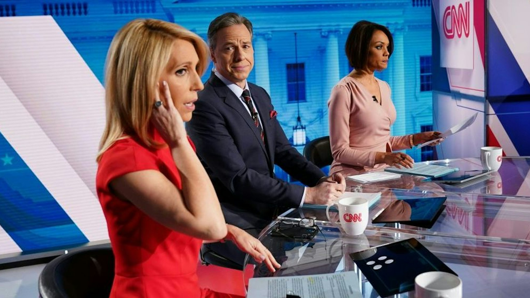 CNN news anchor Jake Tapper (C), flanked by Univision's news anchor Ilia Calderón (R), watches as co-anchor Dana Bash adjusts her ear piece before the start of the 11th Democratic Party 2020 presidential debate with former Vice-President Joe Biden and Vermont Senator Bernie Sanders in a CNN Washington Bureau studio in Washington, DC on March 15, 2020.