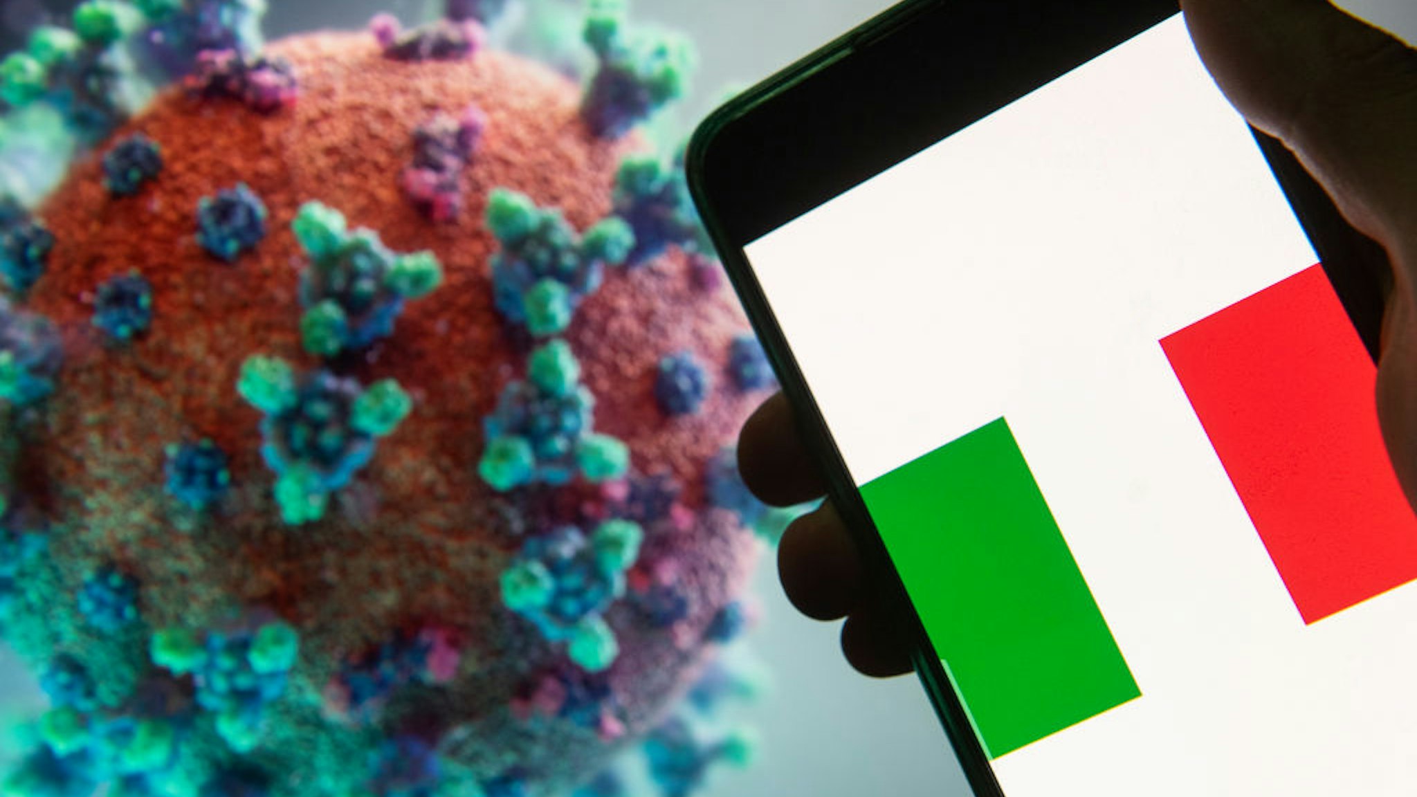 In this photo illustration the Italian Republic flag seen displayed on a smartphone with a computer model of the COVID-19 coronavirus on the background.