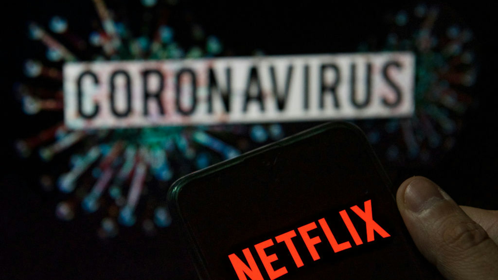 In this photo illustration the American global on-demand Internet streaming media provider Netflix logo seen displayed on a smartphone with a computer model of the COVID-19 coronavirus on the background.