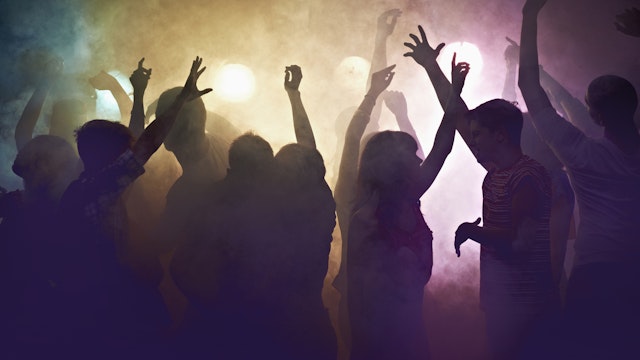 Crowd of people at concert waving arms in the air - stock photo