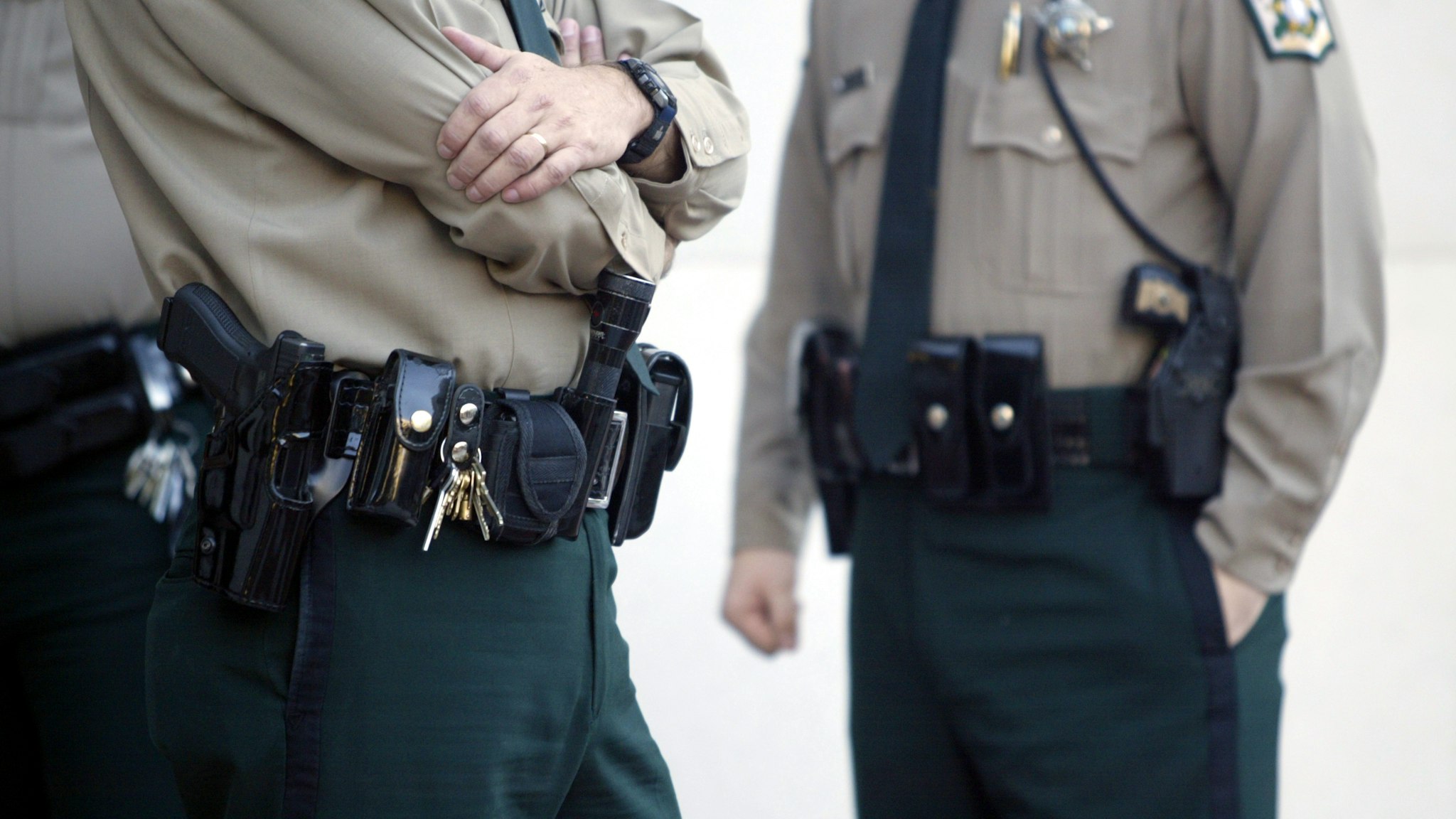 "police officers stand with handguns, stun gun and tools on their holsters."