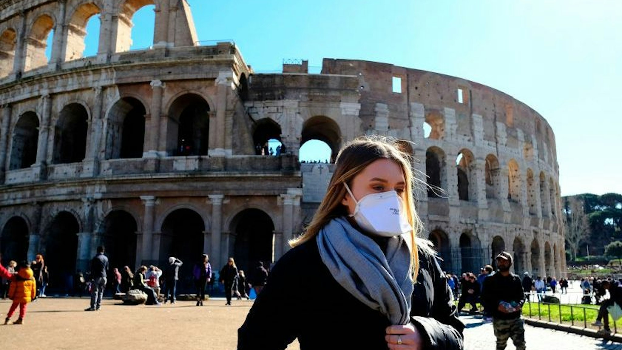 Tourist wearing a protective respiratory mask tours outside the Colosseo monument (Colisee, Coliseum) in downtown Rome on February 28, 2020 amid fear of Covid-19 epidemic. - Since February 23, more than 50,000 people have been confined to 10 towns in Lombardy and one in Veneto -- a drastic measure taken to halt the spread of the new coronavirus, which has infected some 400 people in Italy, mostly in the north.