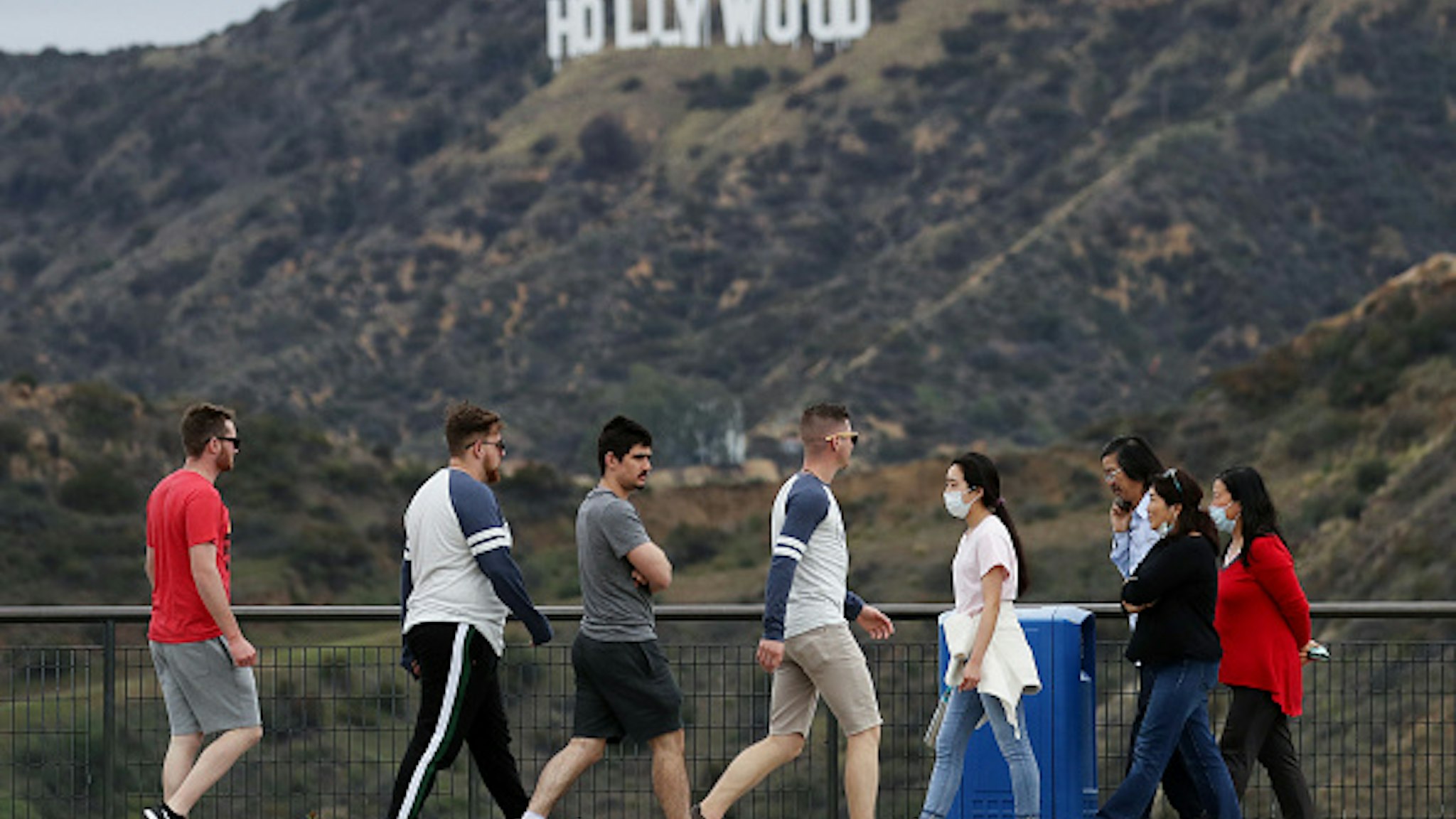LOS ANGELES, CALIFORNIA - MARCH 22: People, some wearing face masks, walk in Griffith Park with the Hollywood sign behind them on March 22, 2020 in Los Angeles, California. California Governor Gavin Newsom issued a ‘stay at home’ order for California’s 40 million residents in order to slow the spread of coronavirus (COVID-19). Californians may still visit parks without violating Newsom’s order as long as they maintain social distancing and adhere to other public health measures related to the coronavirus. Los Angeles Mayor Eric Garcetti today urged Angelenos to practice physical distancing after crowds were seen at some beaches and hiking trails this weekend.