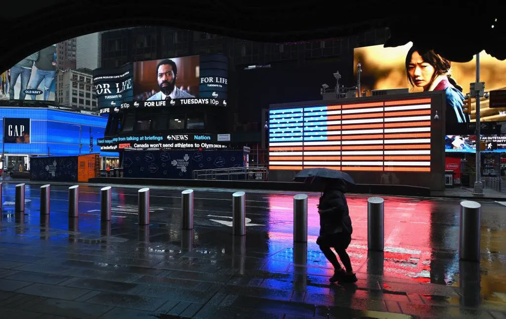 A person with an umbrella passes through Times Square on March 23, 2020 in New York City. - The Big Apple has the highest number of confirmed cases of COVID-19 in the United States and Bill de Blasio said the city's hospitals were at breaking point. (Photo by Angela Weiss / AFP) (Photo by ANGELA WEISS/AFP via Getty Images)