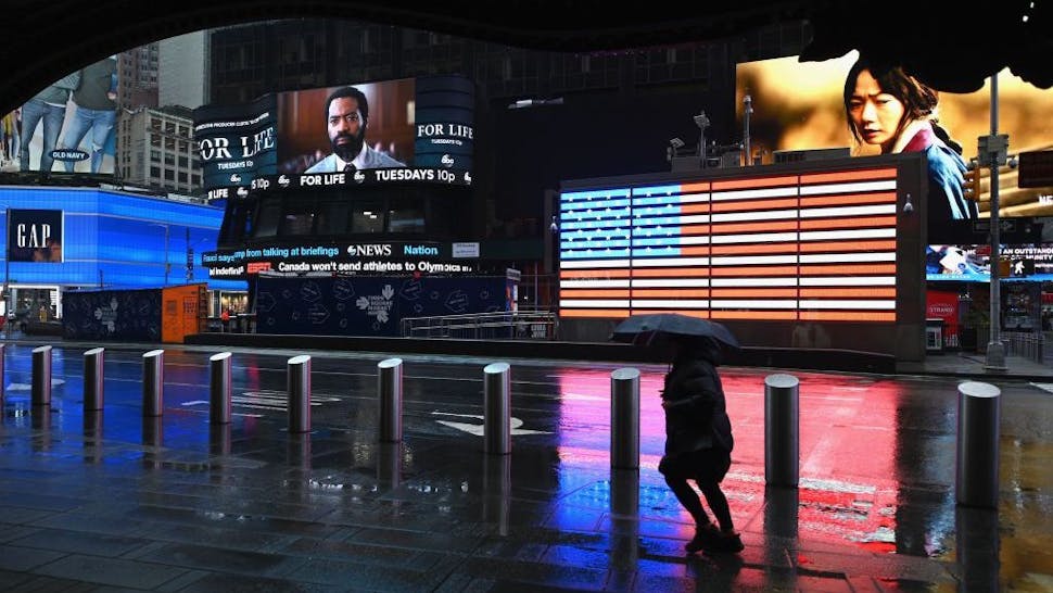 New York City A person with an umbrella passes through Times Square on March 23, 2020 in New York City. - The Big Apple has the highest number of confirmed cases of COVID-19 in the United States and Bill de Blasio said the city's hospitals were at breaking point. (Photo by Angela Weiss / AFP) (Photo by ANGELA WEISS/AFP via Getty Images)