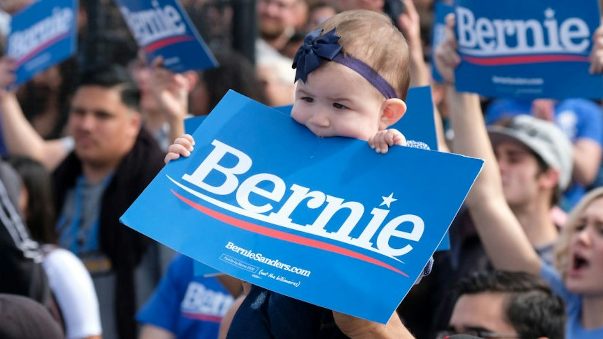 A supporter of Democratic presidential hopeful Vermont Senator Bernie Sanders (not pictured) holds up his baby during a rally at Valley High School in Santa Ana, California, February 21, 2020. (Photo by RINGO CHIU / AFP) (Photo by