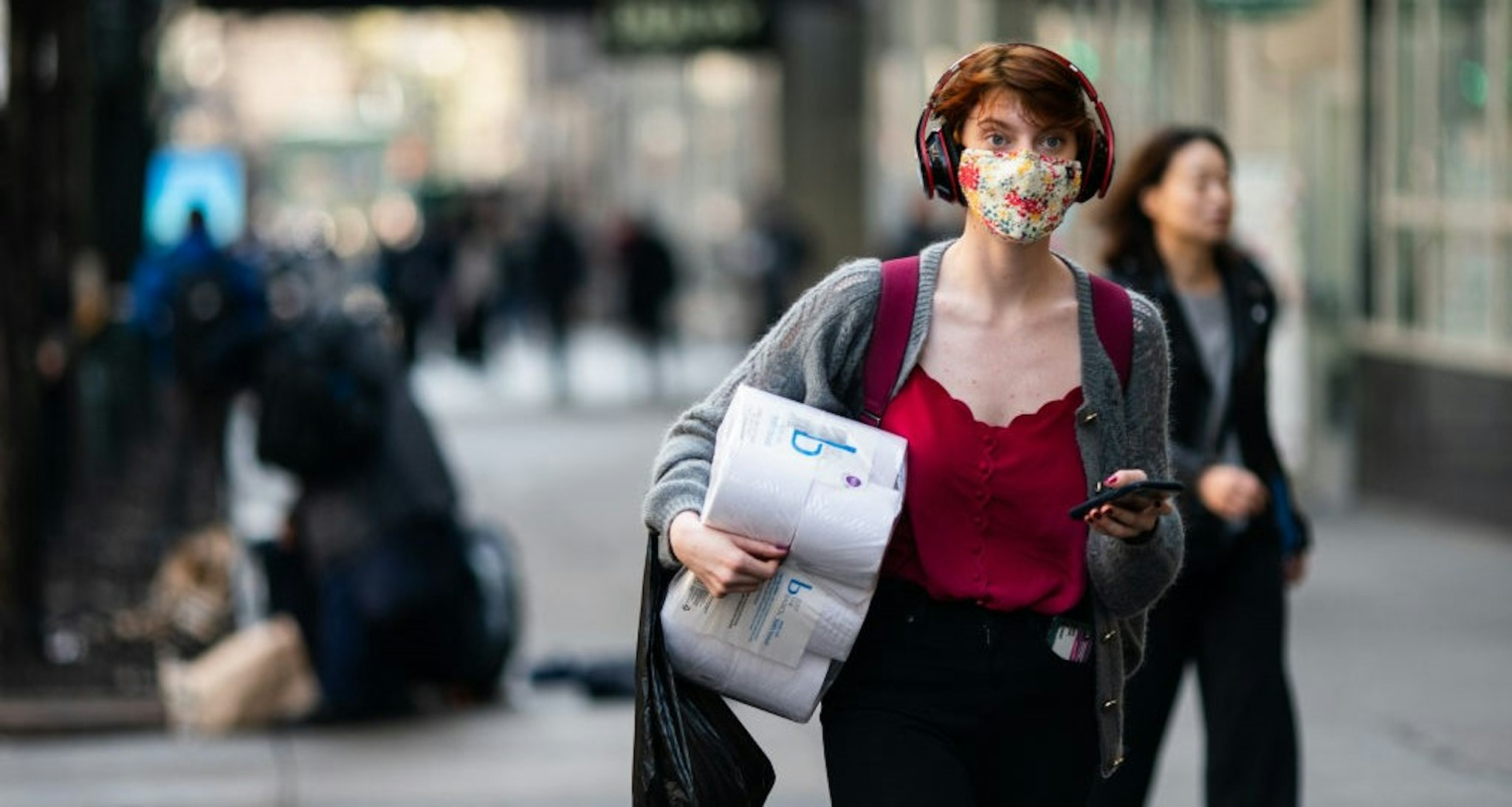 NEW YORK, NY - MARCH 13: A woman wearing a protective mask carries a toilet paper package on the street on March 13, 2020 in New York City. President Donald Trump is expected to declare national emergency over coronavirus crisis today. There are at least 95 confirmed cases in New York City. (Photo by