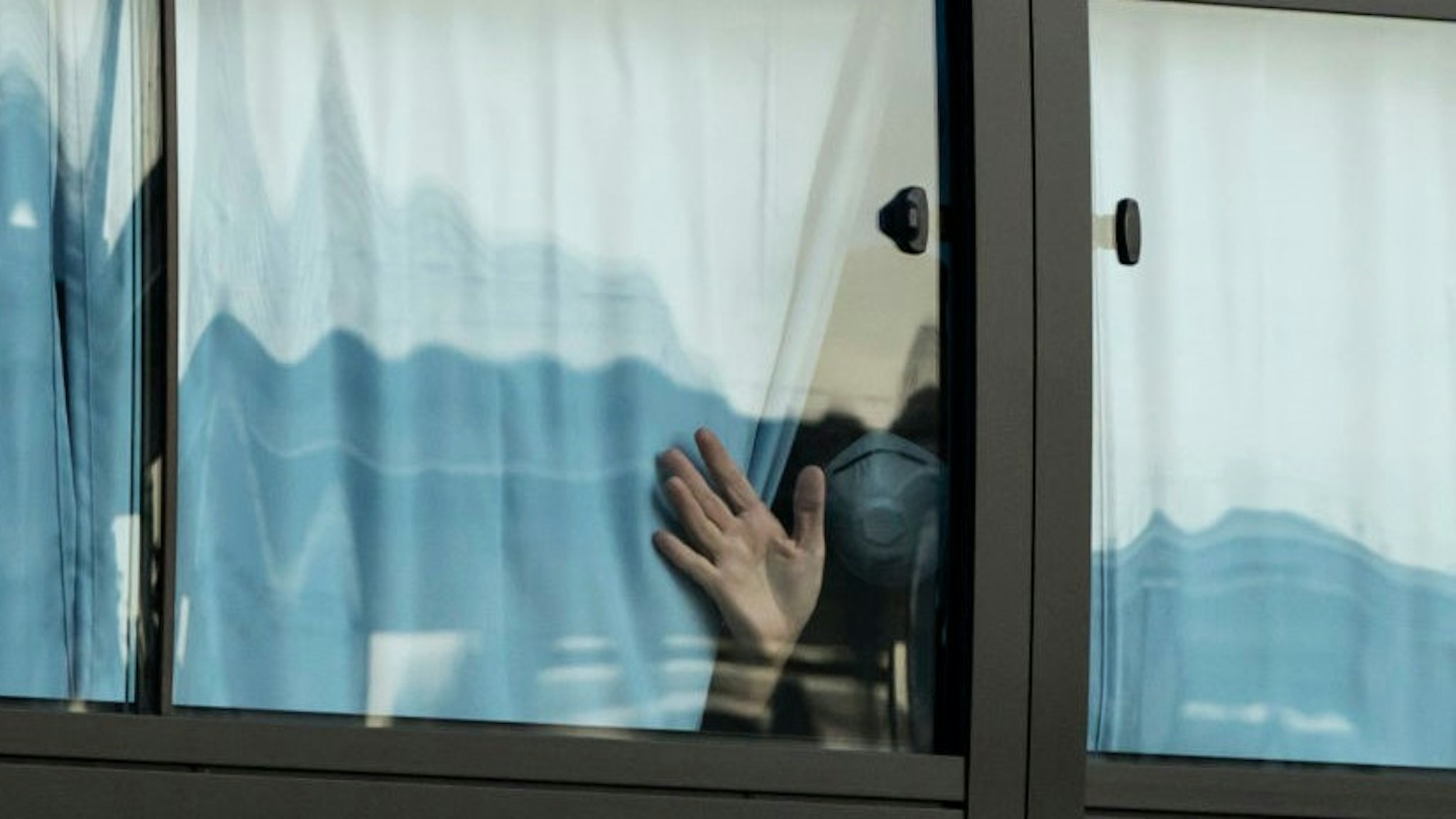 YOKOHAMA, JAPAN - FEBRUARY 19: A man waves from a bus carrying passengers who disembarked the quarantined Diamond Princess cruise ship as he leaves the Daikoku Pier on February 19, 2020 in Yokohama, Japan. About 500 passengers who have tested negative for the coronavirus (COVID-19) were allowed to disembark the cruise ship on Wednesday after 14 days quarantine period as at least 542 passengers and crew onboard have tested positive for the coronavirus. Including cases onboard the ship, 615 people in Japan have now been diagnosed with COVID-19 making it the worst affected country outside of China. (Photo by