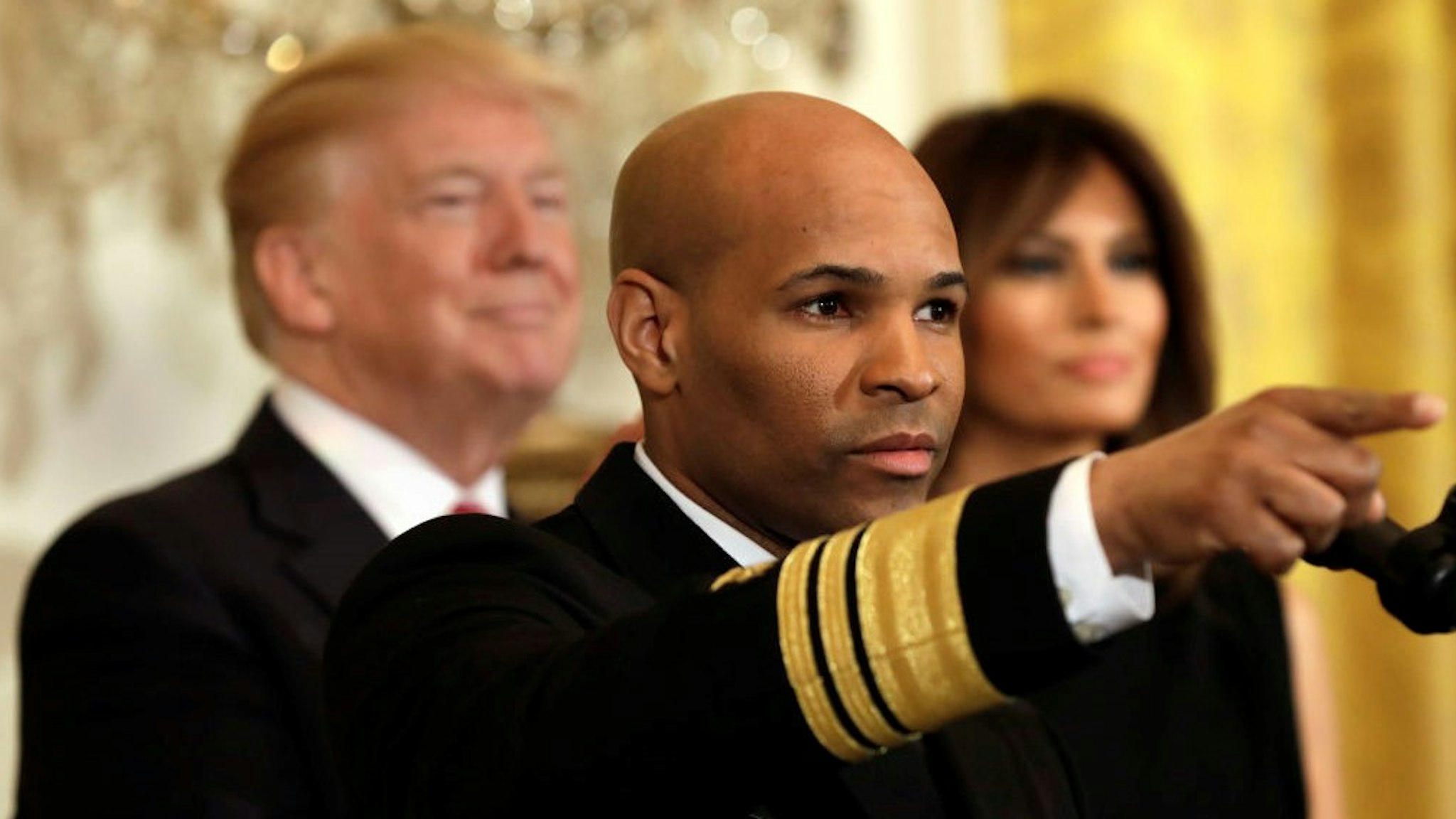 Vice Admiral Jerome Adams, the U.S. Surgeon General, gestures while speaking at an event with U.S. President Donald Trump and First Lady Melania Trump during a National African American History Month reception in Washington, D.C., U.S., on Tuesday, Feb. 13, 2018. U.S. President Donald Trump's move to end a program protecting hundreds of thousands of children of undocumented immigrants from deportation was blocked by a federal judge in New York. Its the second time in less than two months that a U.S. judge found the rescinding of the program as proposed would be wrong. Photographer: