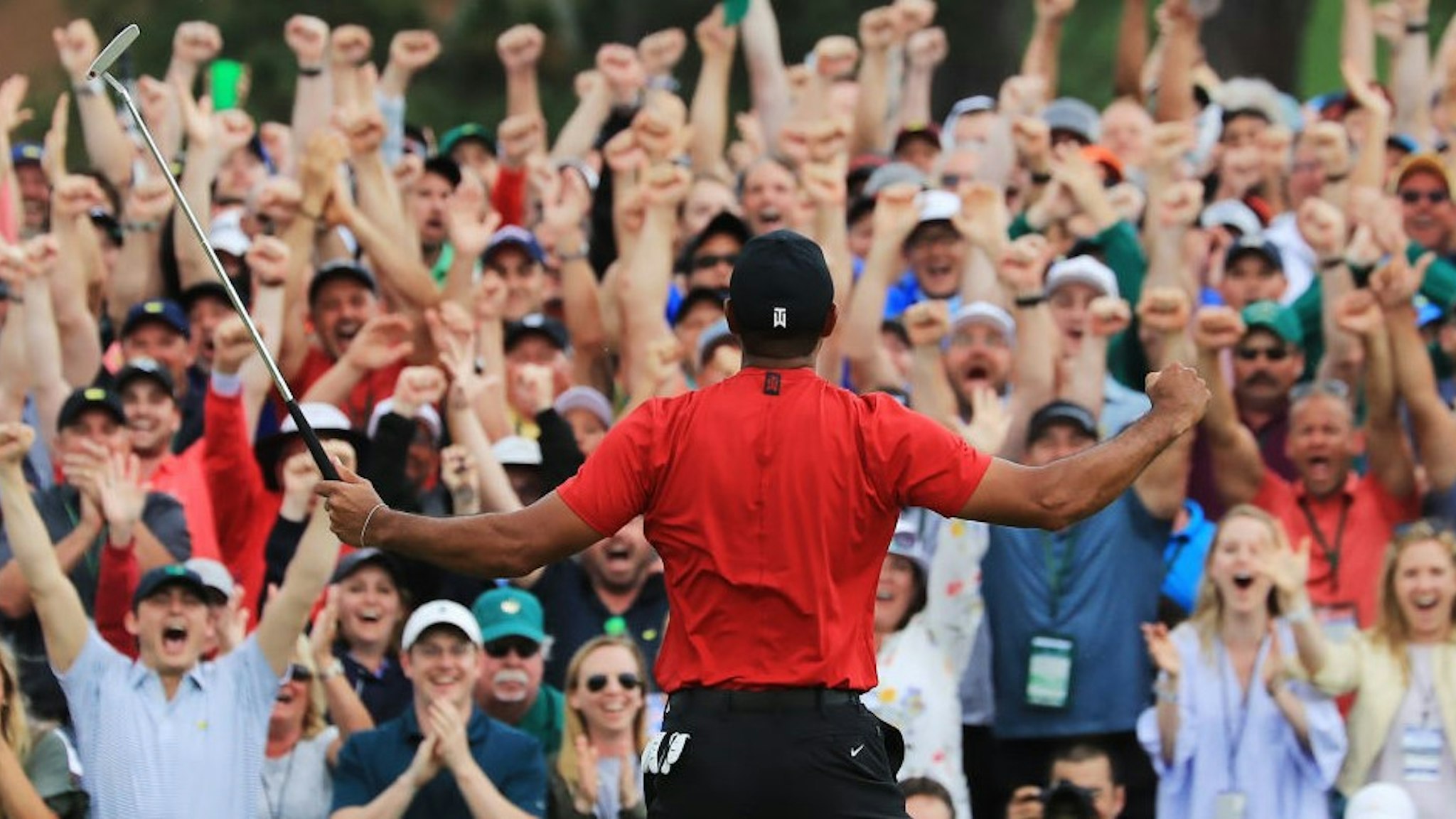 AUGUSTA, GEORGIA - APRIL 14: Patrons cheer as Tiger Woods of the United States celebrates after sinking his putt on the 18th green to win during the final round of the Masters at Augusta National Golf Club on April 14, 2019 in Augusta, Georgia. (Photo by