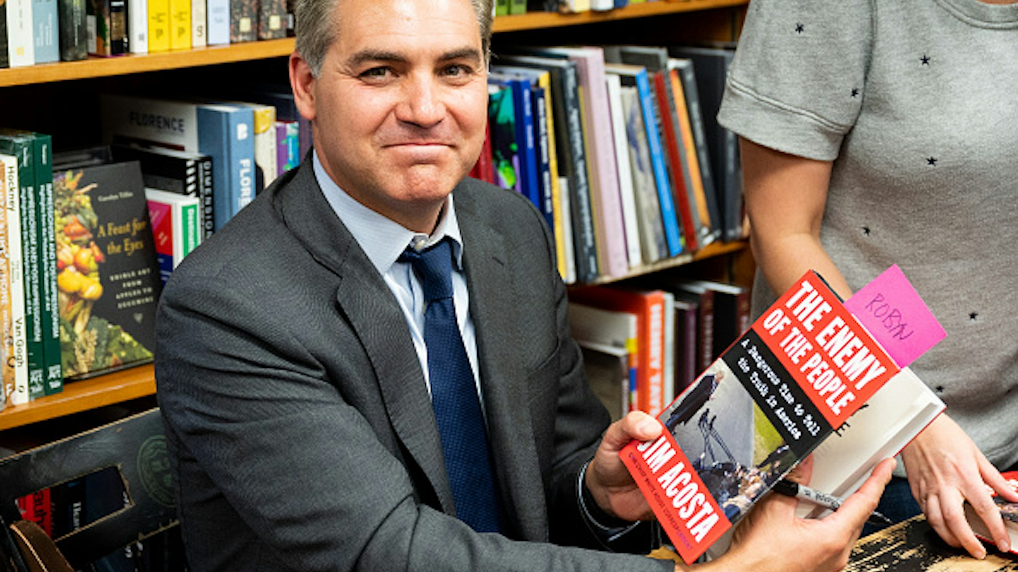 WASHINGTON, D C , UNITED STATES - 2019/06/18: Jim Acosta holds his book "The Enemy of the People: A Dangerous Time to Tell the Truth in America" at the Politics and Prose bookstore in Washington, DC.