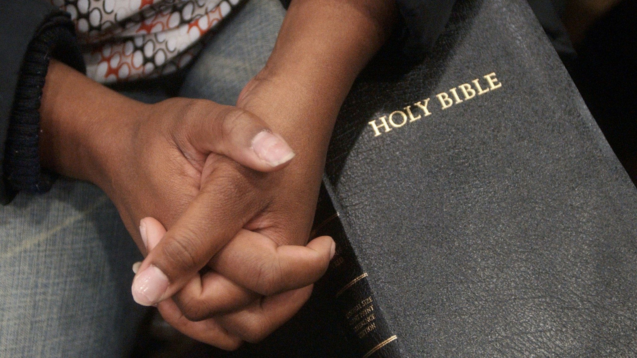 Shontae Scott of Atlanta clutches her hands on her bible Tuesday while watching live coverage of the funeral of Coretta Scott King at the Samson's Health and Fitness Center next to the New Birth Missionary Baptist Church February 7, 2006 in Lithonia, Georgia.