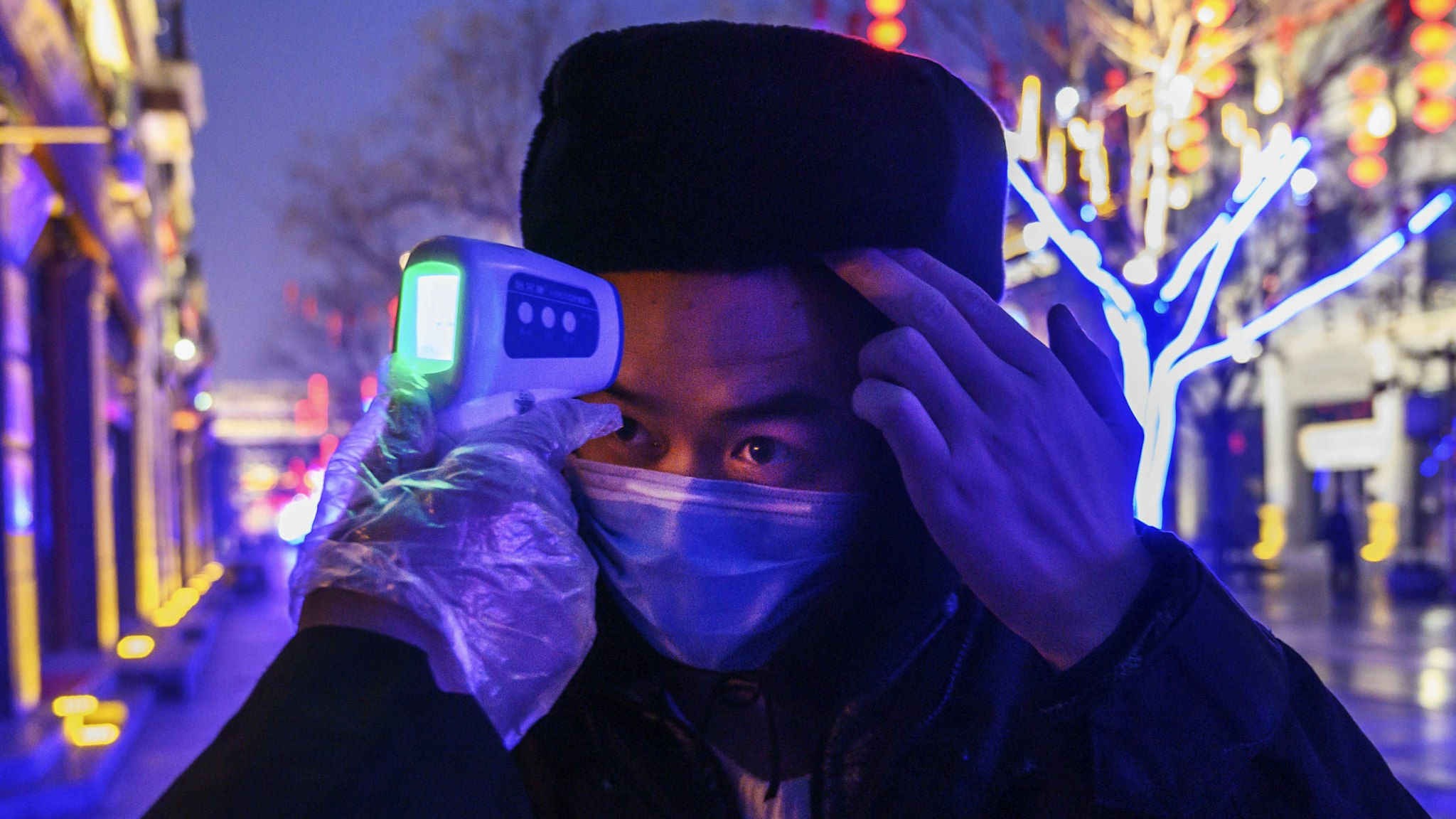 BEIJING, CHINA - FEBRUARY 12: A Chinese worker wears a protective mask as he has his temperature checked in a nearly empty and shuttered commercial street on February 12, 2020 in Beijing, China. The number of cases of a deadly new coronavirus rose to more than 44000 in mainland China Wednesday, days after the World Health Organization (WHO) declared the outbreak a global public health emergency. China continued to lock down the city of Wuhan in an effort to contain the spread of the pneumonia-like disease which medicals experts have confirmed can be passed from human to human. In an unprecedented move, Chinese authorities have put travel restrictions on the city which is the epicentre of the virus and municipalities in other parts of the country affecting tens of millions of people. The number of those who have died from the virus in China climbed to over 1100 on Wednesday, mostly in Hubei province, and cases have been reported in other countries including the United States, Canada, Australia, Japan, South Korea, India, the United Kingdom, Germany, France and several others. The World Health Organization has warned all governments to be on alert and screening has been stepped up at airports around the world. Some countries, including the United States, have put restrictions on Chinese travellers entering and advised their citizens against travel to China.