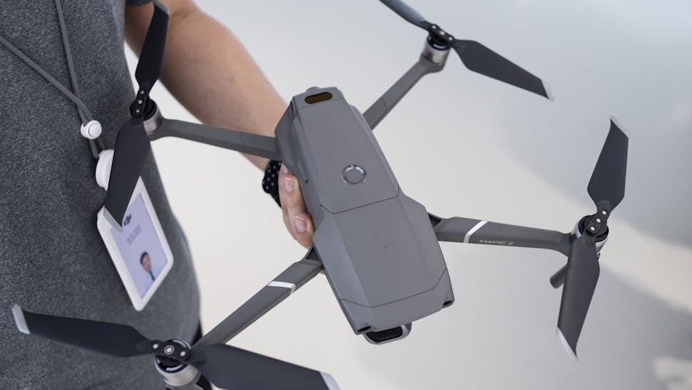 An employee from Chinese Technology company DJI holds the CAUSEWAY BAY, HONG KONG, HONG KONG ISLAND, CHINA - 2018/08/24: An employee from Chinese Technology company DJI holds the new DJI Mavic 2 Pro drone a day after it was officially announced its release at its flagship store in Hong Kong. Drone manufacturing leader DJI releases 2 of it's latest products, the Marvic 2 pro and the Marvic 2 zoom on 23rd August 2018. The Marvic 2 Pro is equipped with a upgraded 1 inch camera sensor for improved quality, while the Marvic 2 zoom allows users to use the digital zoom function in flight.
