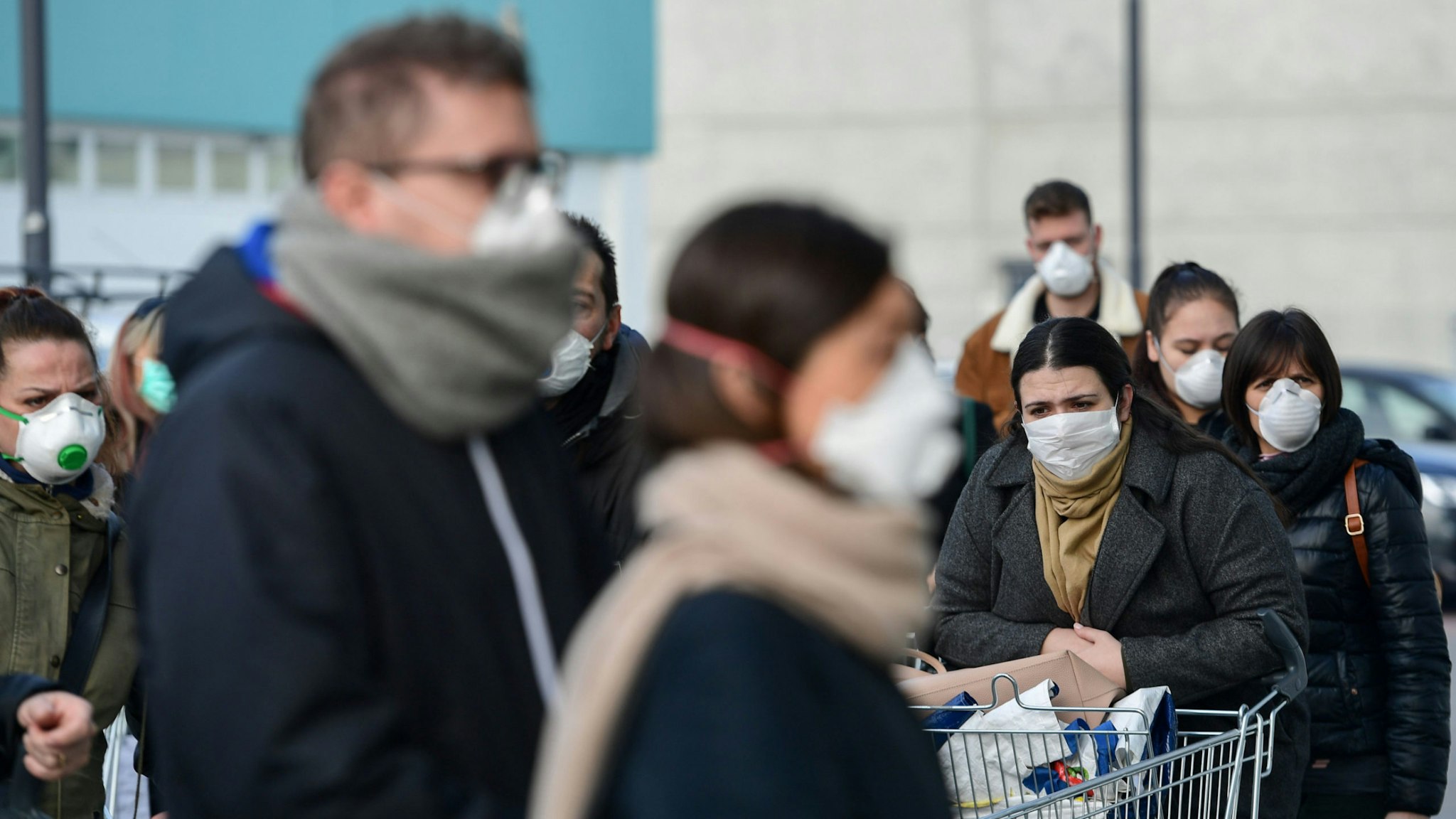 Residents wearing respiratory mask wait to be given access to shop in a supermarket in small groups of forty people on February 23, 2020 in the small Italian town of Casalpusterlengo, under the shadow of a new coronavirus outbreak, as Italy took drastic containment steps as worldwide fears over the epidemic spiralled.