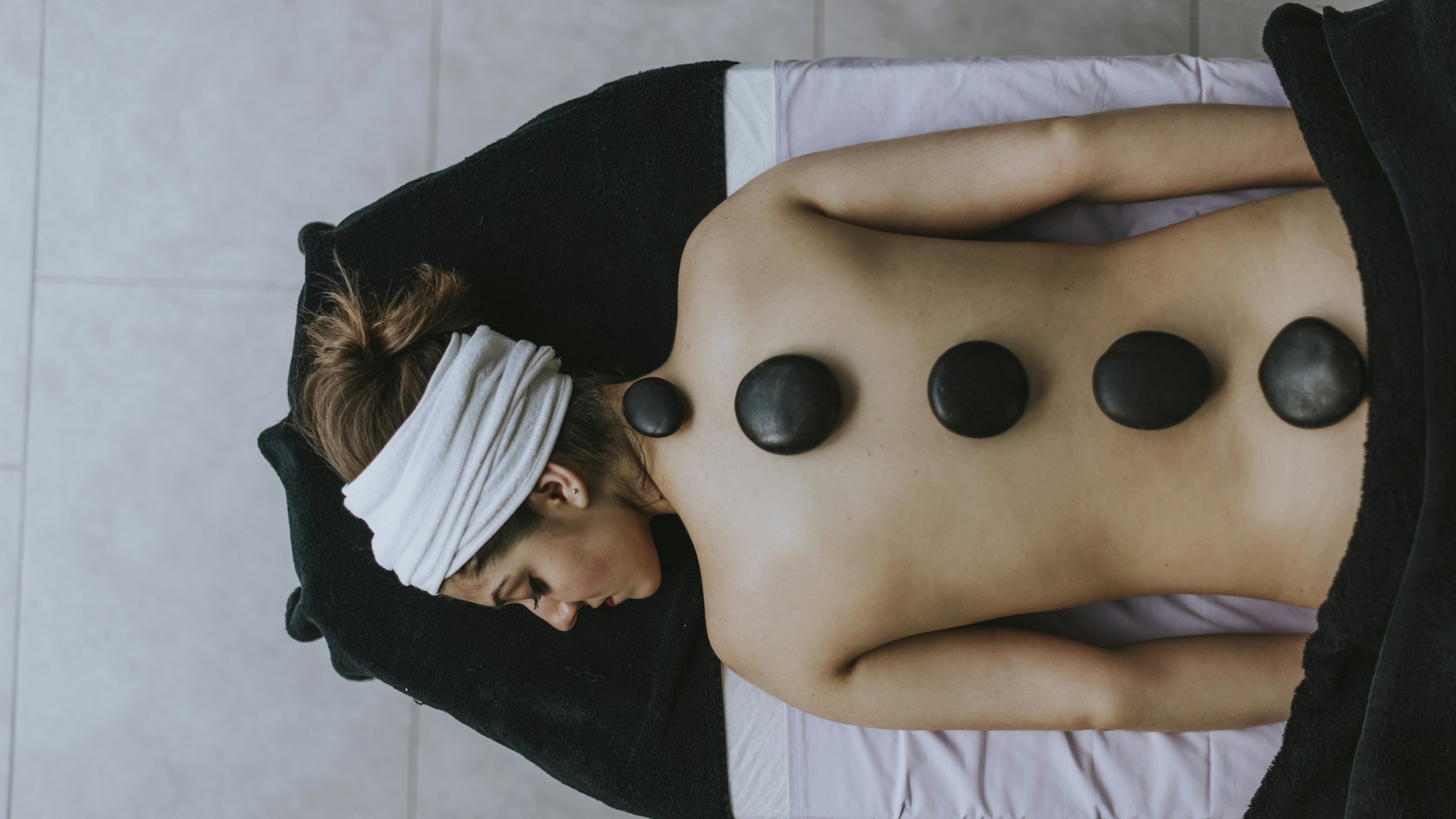 Young woman with heated stones on her back - stock photo