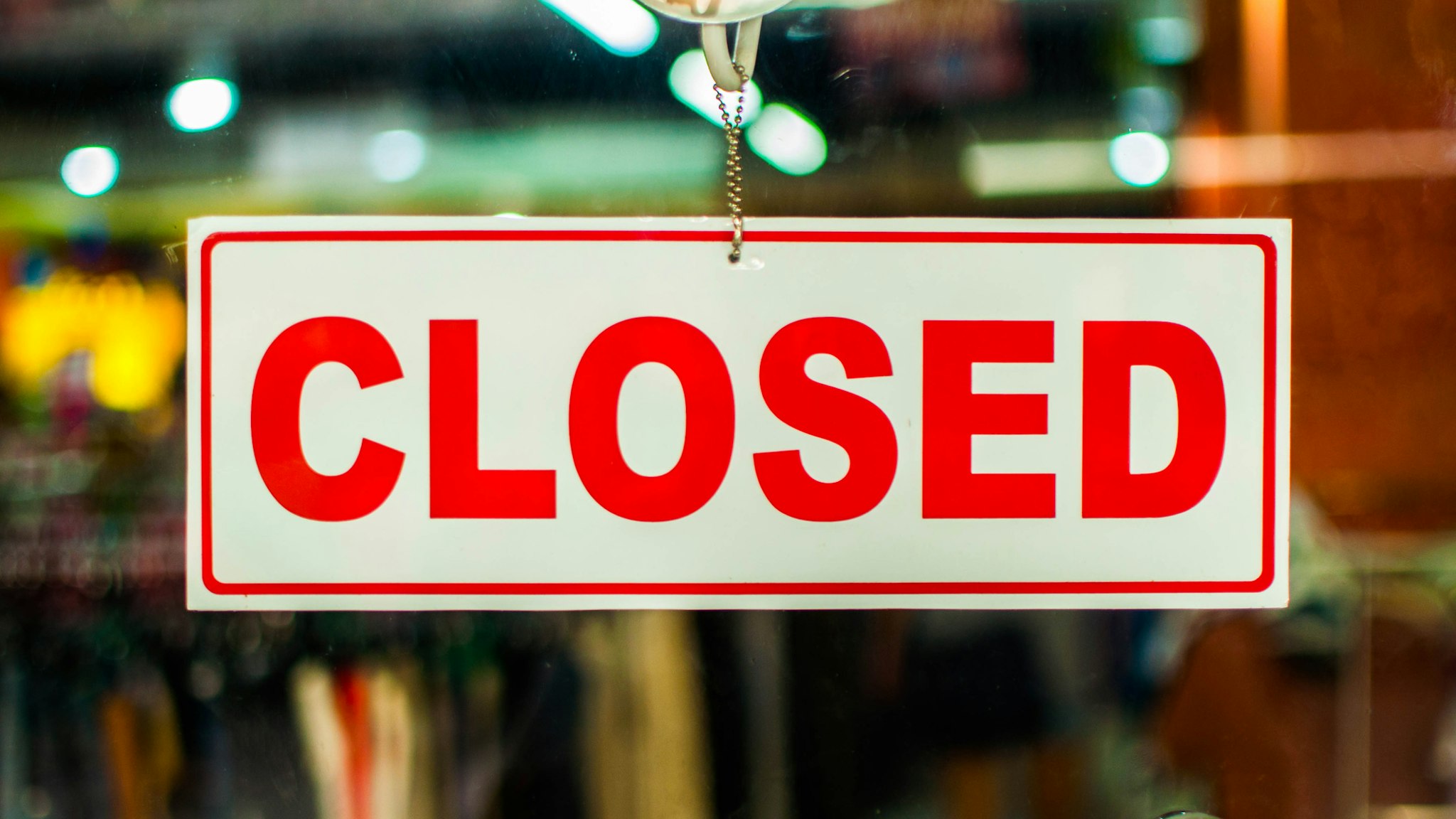 A glass door with red and white "closed" store sign