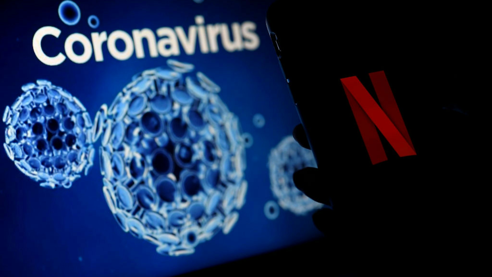 In this photo illustration a mobile phone screens display the Netflix logo on a coronavirus COVID-19 illustration graphic background , March 31, 2020 in Arlington, Virginia.