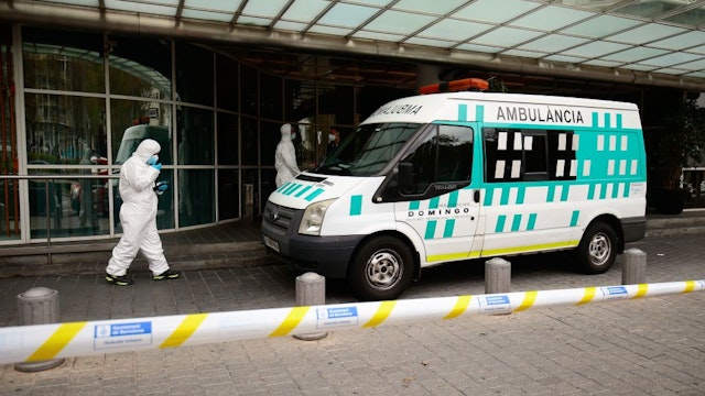 Healthcare workers wearing protective suits enter an ambulance in front of the Hotel Melia Barcelona Sarria on April 2, 2020 in Barcelona, as the hotel was transformed into a medical structure to treat the least serious cases amid the outbreak caused by the novel coronavirus.