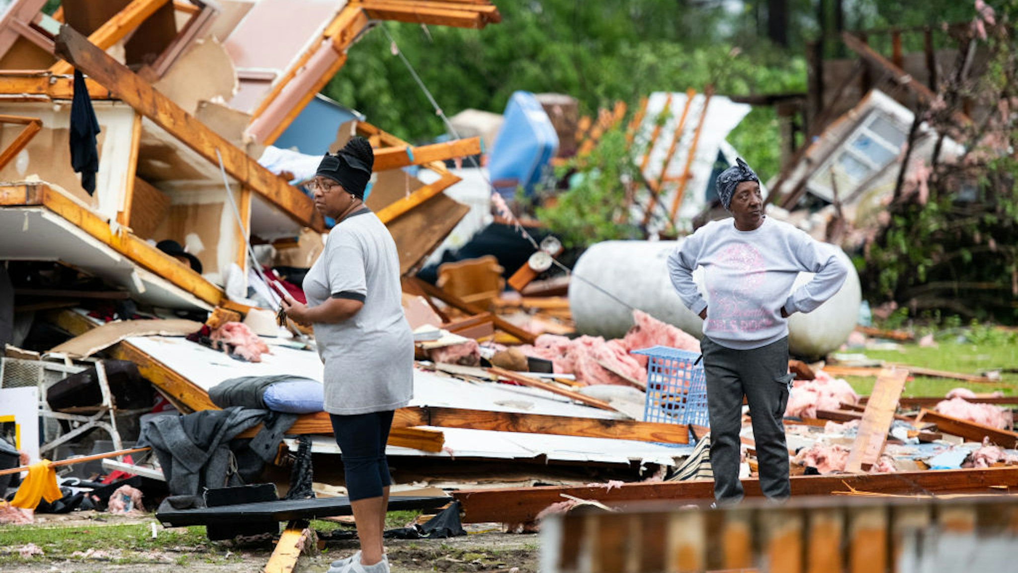 Sylvia Salley, right, and Evelyn Wise looks over what remains of a storm damaged home April 13, 2020 in Livingston, South Carolina. A string of storms caused more than a dozen deaths across the southern United States.