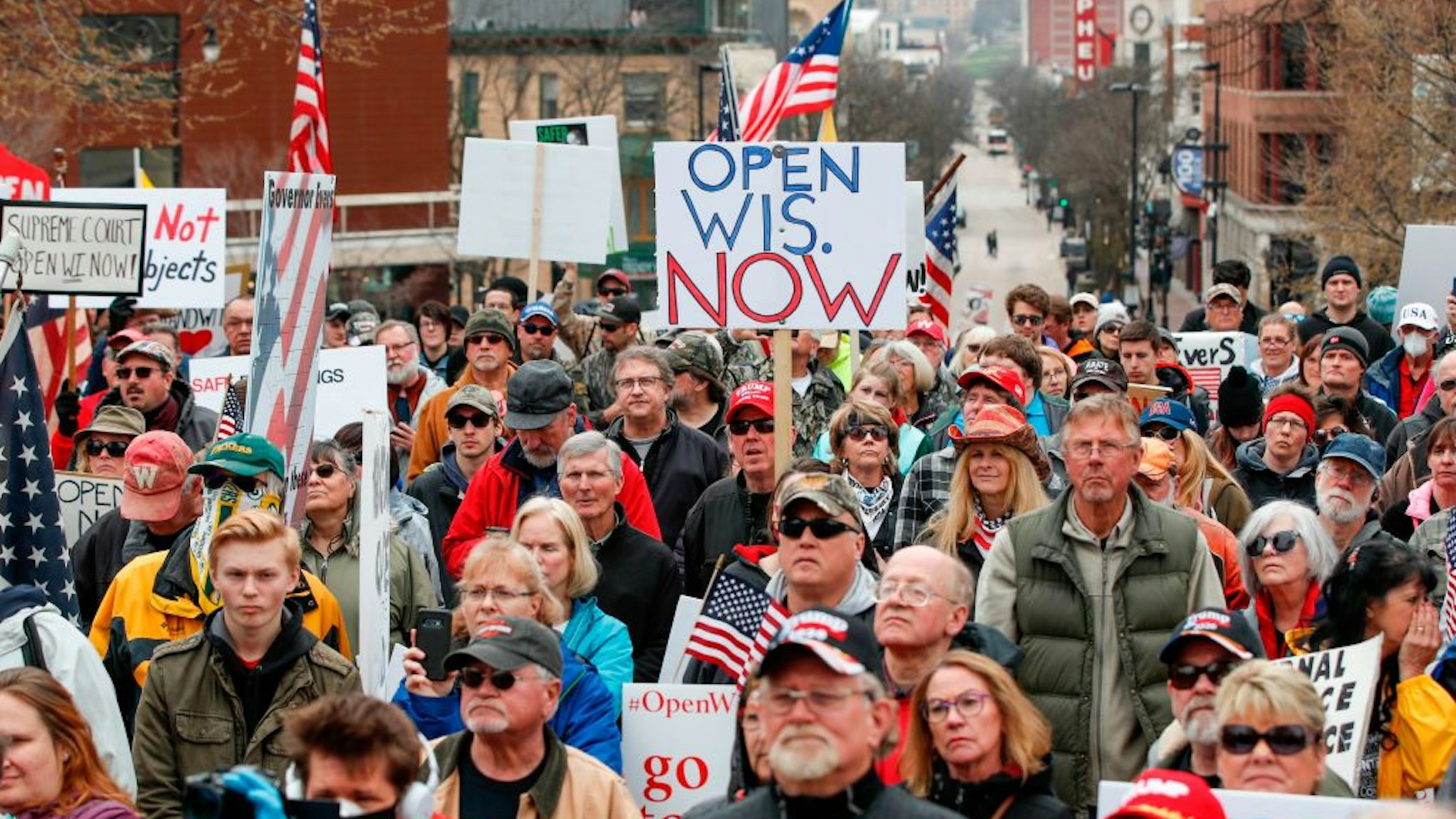 People hold signs during a protest against the coronavirus shutdown in front of State Capitol in Madison, Wisconsin, on April 24, 2020.