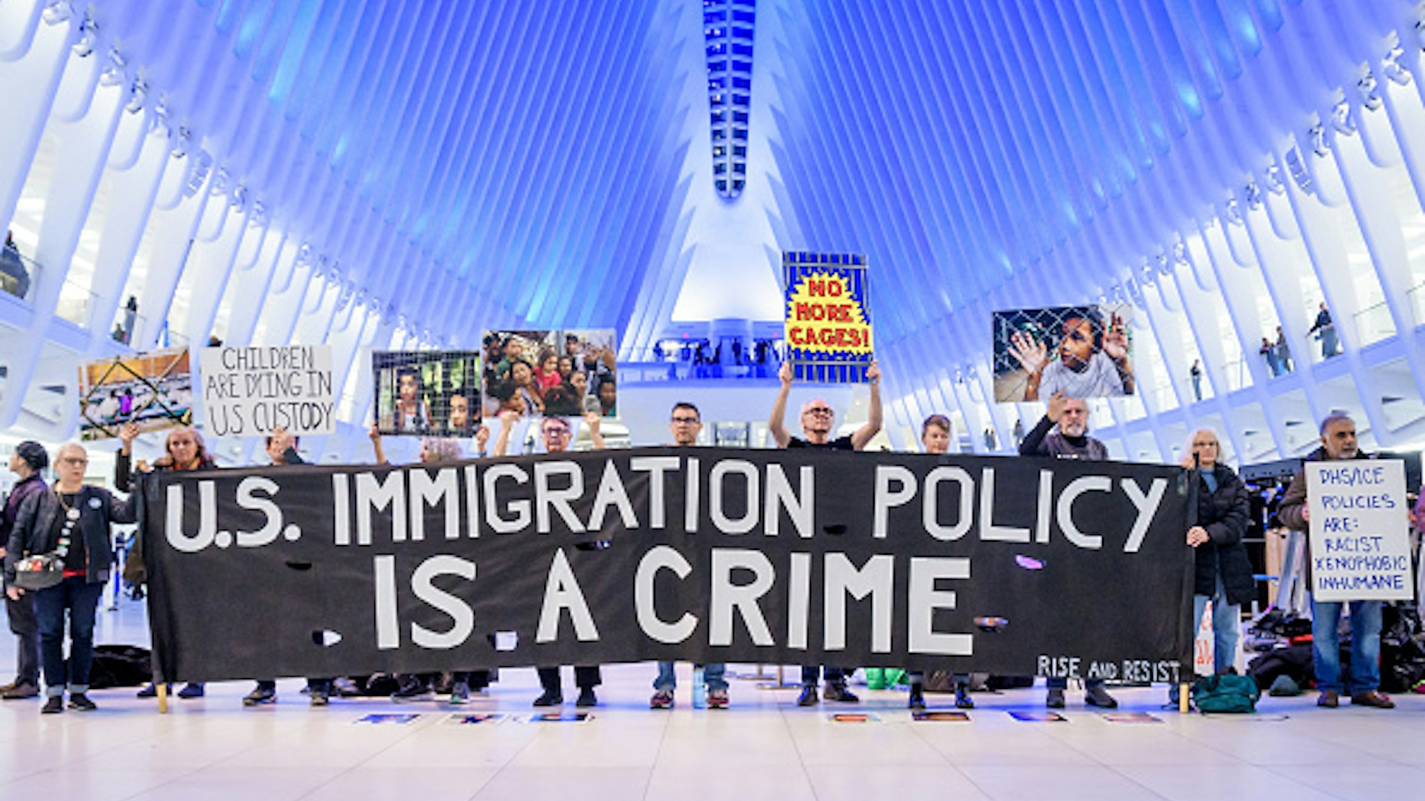 MANHATTAN, NEW YORK, UNITED STATES - 2020/01/06: Protesters holding a banner at the silent protest. Members of the activist group Rise And Resist gathered a silent protest inside The Oculus at the World Trade Center, holding protest signs, a banner reading "U.S. Immigration Policy Is A Crime", photographs of the children who have died in ICE custody, and photographs of the detention camps to object to Border Patrol and ICE treatment of immigrants, refugees, and asylum seekers, calling on the Trump administration to immediately process all asylum seekers.