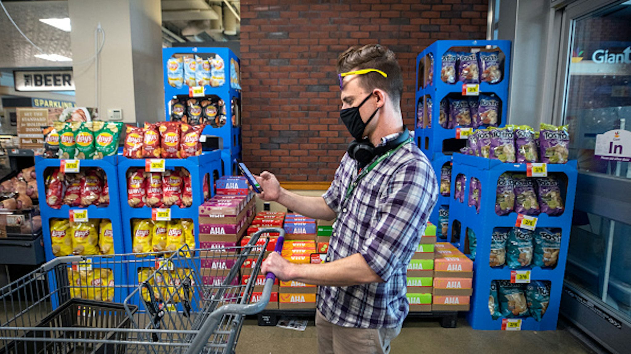 WASHINGTON,DC-APR6: Matt Gillette, a 36 year-old Instacart shopper, prepares to fulfill an order at a Giant supermarket in Washington, DC, April 6, 2020. For the past two years he's been part of the gig economy, driving for Lyft, doing handiwork on TaskRabbit. The work was so unstable he's been on the verge of homelessness, crashing with some friends and asking others to take in his beloved dog, a lab mix named Nitro. For years there has been talk of a divided America, of an economy that's highly beneficial to some and detrimental to others. The wrath of a highly contagious, sometimes lethal virus has shown us where, precisely, it stands: at the front door. On one side are people who have the luxury of staying safely at home, working -- or not -- and ordering whatever they want to be delivered. On the other side are those doing the delivering.