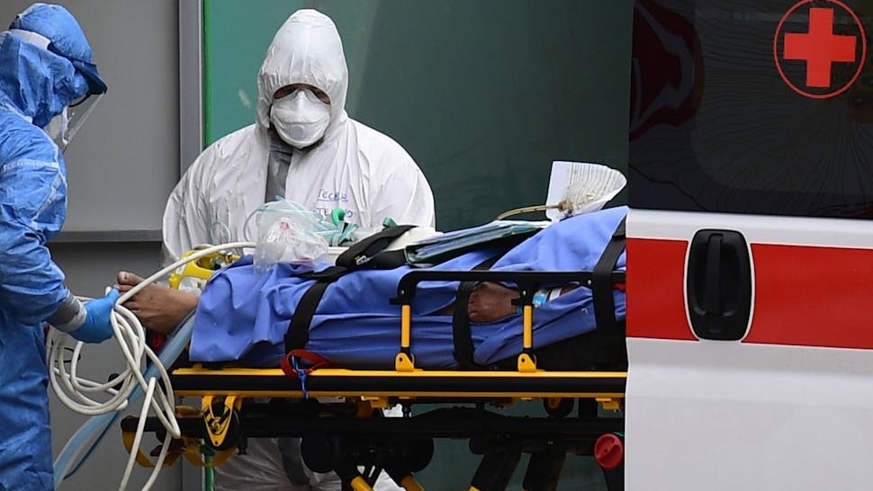 Medical workers stretch a patient from an Italian Red Cross ambulance into an intensive care unit set up in a sports center outside the San Raffaele hospital in Milan, on March 23, 2020 during the COVID-19 new coronavirus pandemic.