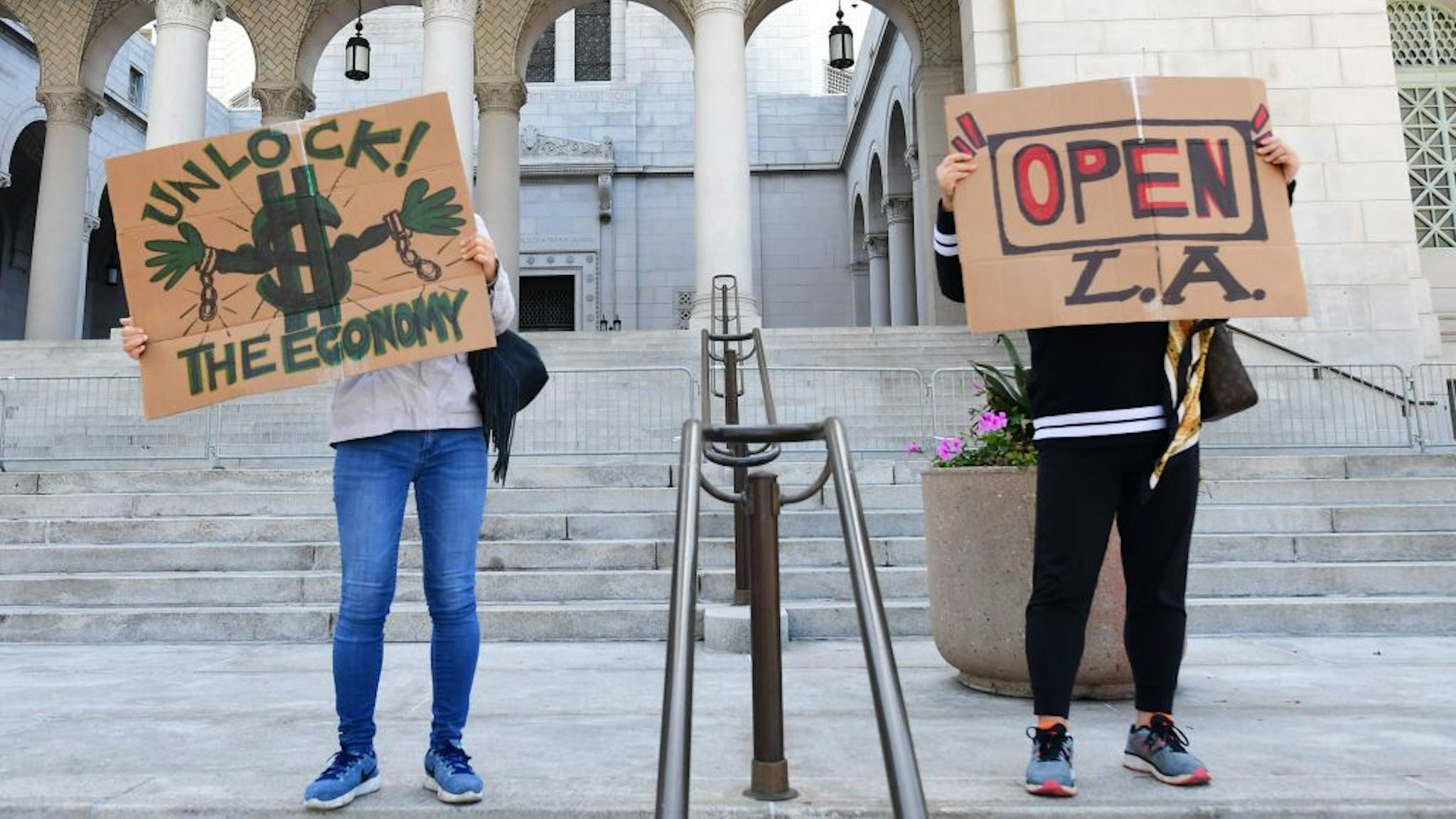 Protestors display placards on the steps of City Hall, demanding the "Stay at Home" order to be lifted and the government to re-open the state during an "Open California" rally in downtown Los Angeles, on April 22, 2020. - Over the past week there have been scattered protests in several US states against confinement measures, from New Hampshire, Maryland and Pennsylvania to Texas and California. (Photo by Frederic J. BROWN / AFP) (Photo by FREDERIC J. BROWN/AFP via Getty Images)