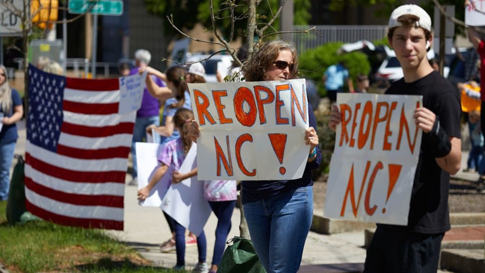 Protesters from a grassroots organization called REOPEN NC demonstrate against the North Carolina coronavirus lockdown at a parking lot adjacent to the North Carolina State Legislature in Raleigh, North Carolina, on April 14, 2020. - The group was demanding the state economy be opened up no later than April 29. (Photo by Logan Cyrus / AFP)