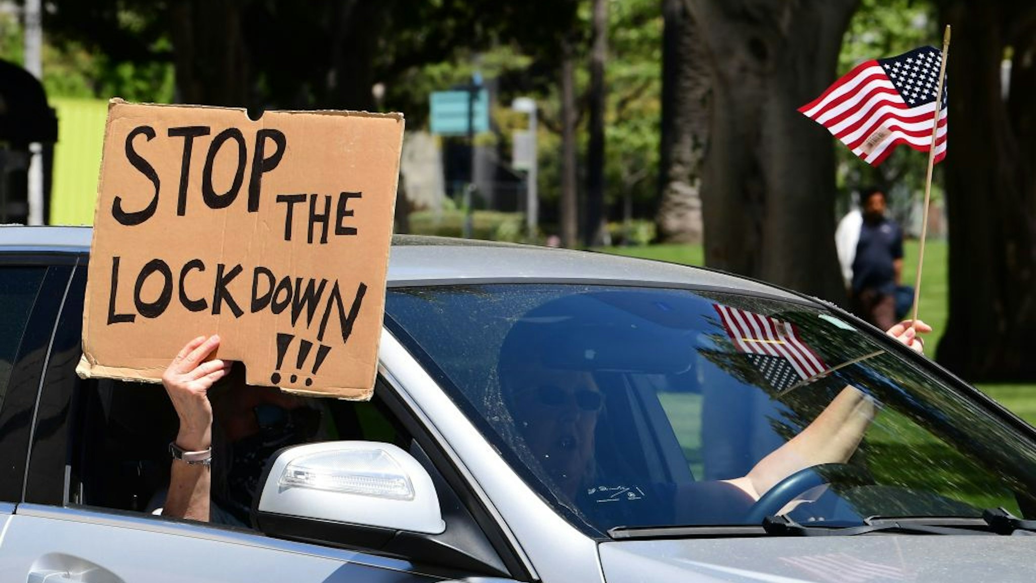 Protesters display placards and flags from their vehicle demanding the "Stay at Home" order to be lifted and the government to re-open the state during an "Open California" rally in downtown Los Angeles, on April 22, 2020. - Over the past week there have been scattered protests in several US states against confinement measures, from New Hampshire, Maryland and Pennsylvania to Texas and California. (Photo by Frederic J. BROWN / AFP) (Photo by FREDERIC J. BROWN/AFP via Getty Images)