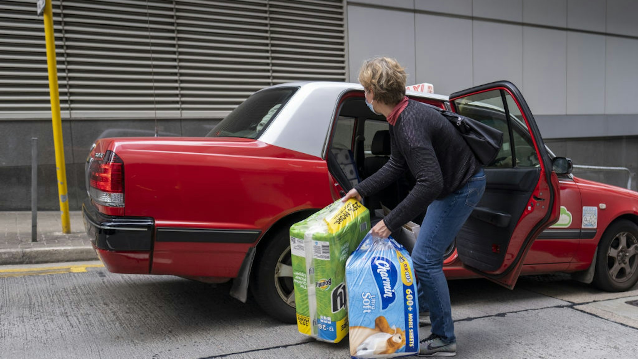A woman loads newly purchased toilet paper and tissues into a taxi in Hong Kong, China, on Thursday, Feb. 6, 2020. Hong Kong has been struggling with a shortage of face masks to protect against the coronavirus outbreak. Now it could be facing a run on toilet paper.