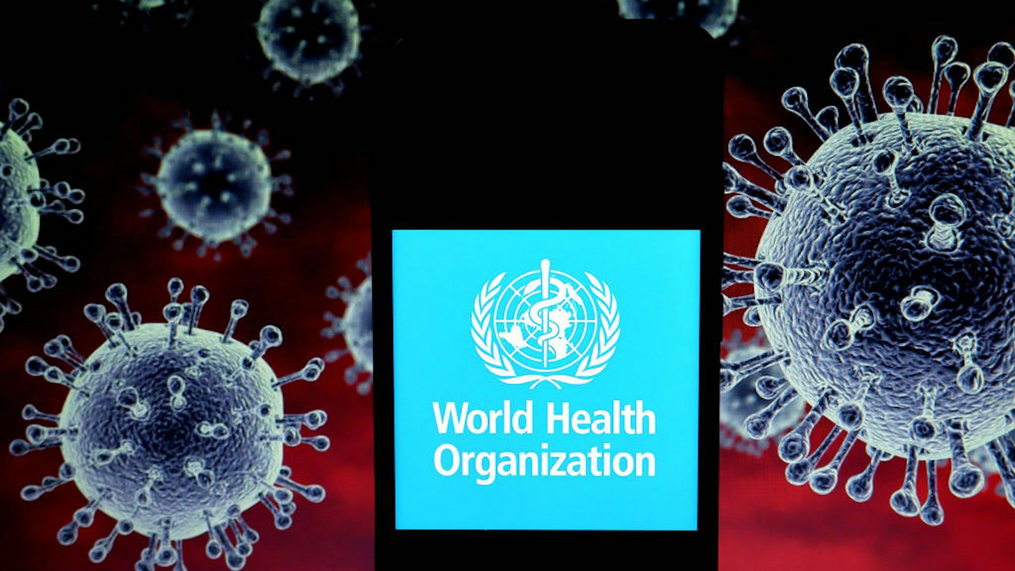 In this photo illustration a World Health Organisation (WHO) logo seen displayed on a smartphone with a computer model of the COVID-19 coronavirus in the background. (Photo Illustration by Avishek Das/SOPA Images/LightRocket via Getty Images)