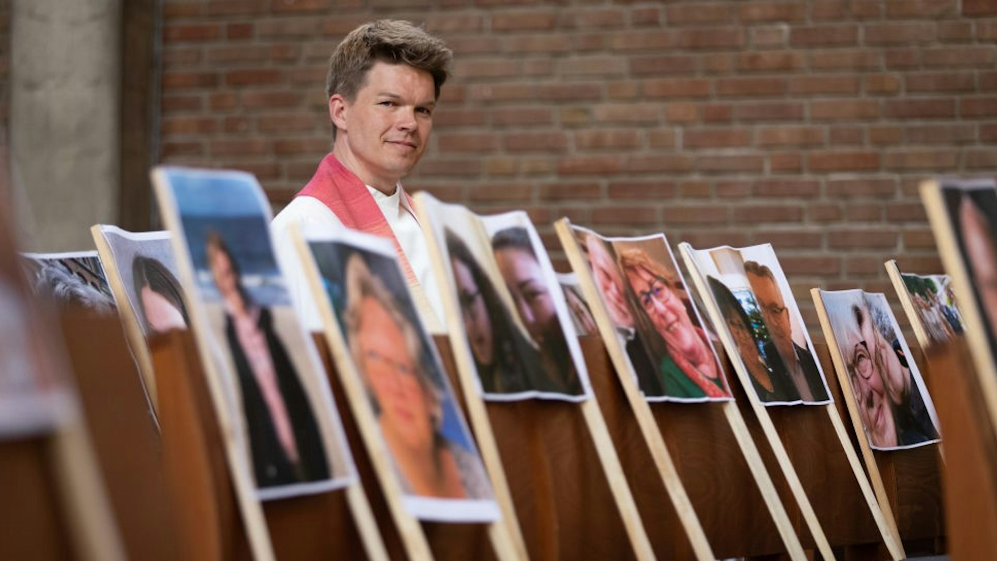 Lower Saxony, Nordhorn: Pastor Simon de Vries from the Lutheran congregation sits in the Christuskirche. In the pews there are photos of believers who are currently unable to attend church services in person because of the Corona crisis.
