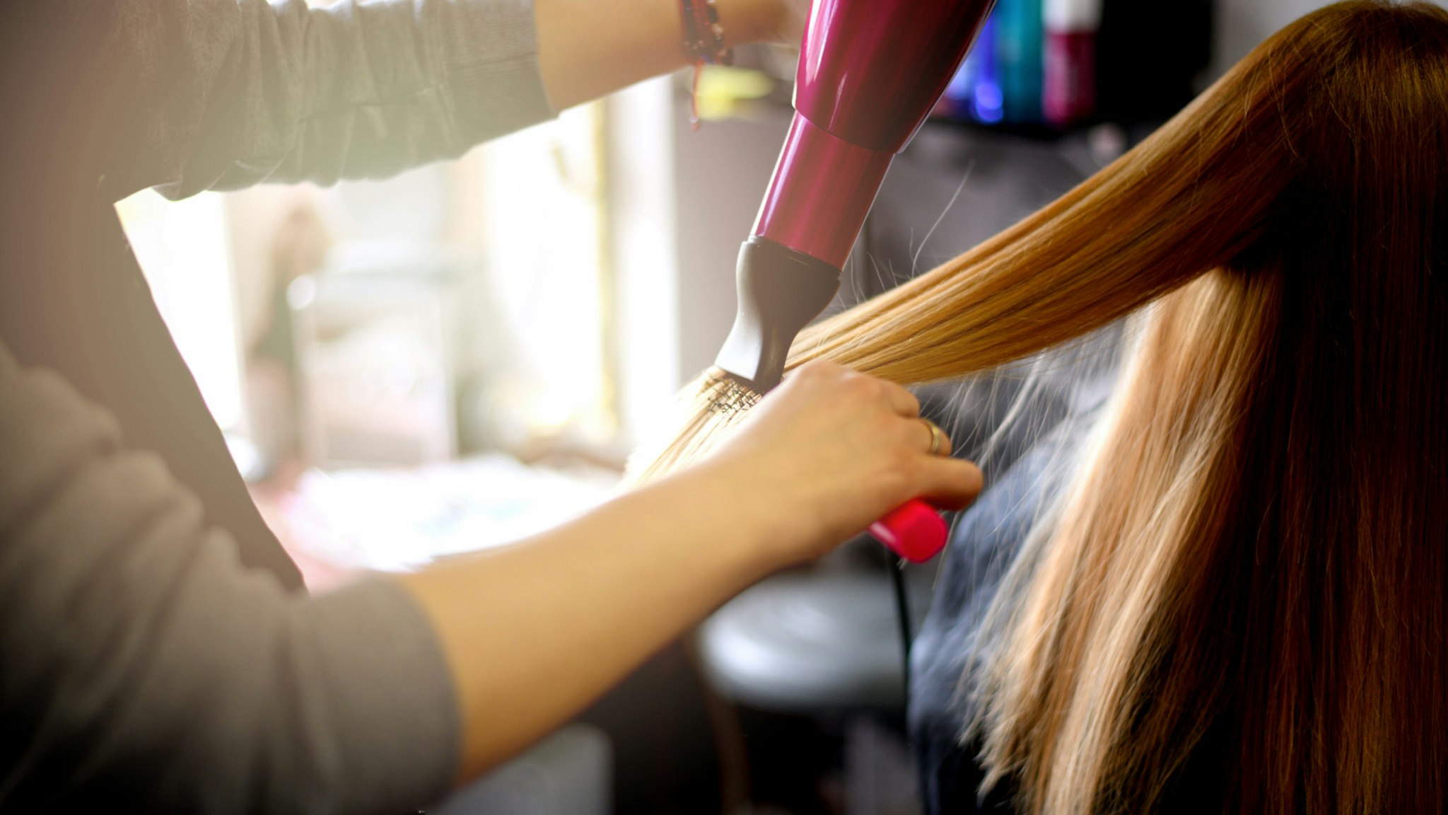 Young beautiful woman having her hair dried at hair salon.