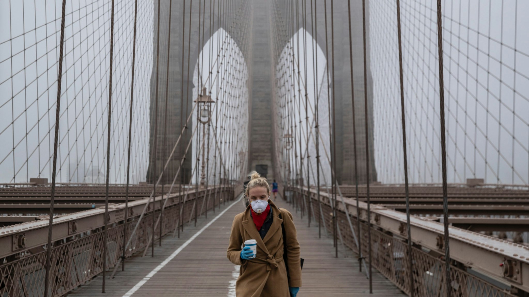 A woman wearing a mask walks the Brooklyn Bridge in the midst of the coronavirus (COVID-19) outbreak on March 20, 2020 in New York City.