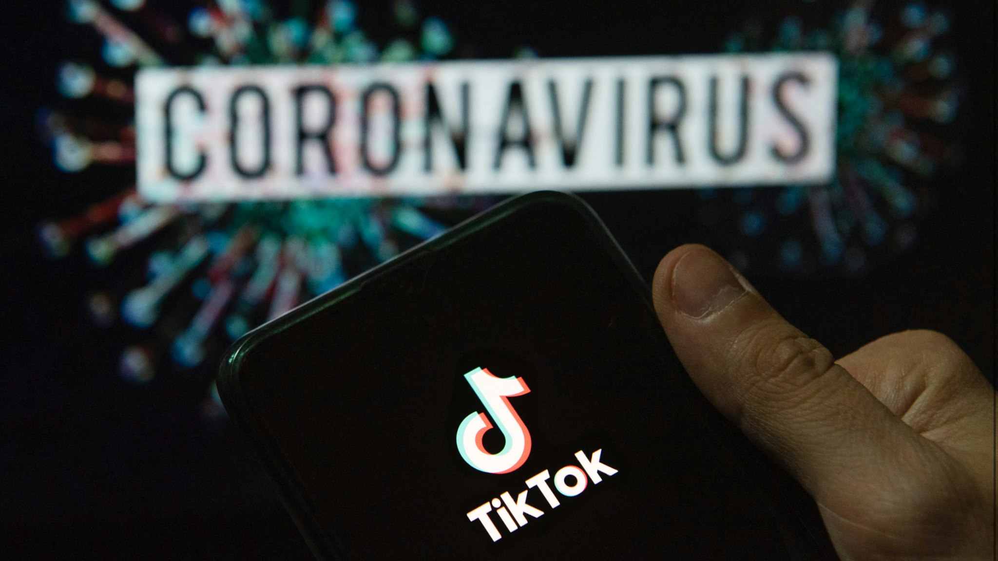 In this photo illustration the Chinese video-sharing social networking service company TikTok logo seen displayed on a smartphone with a computer model of the COVID-19 coronavirus on the background.